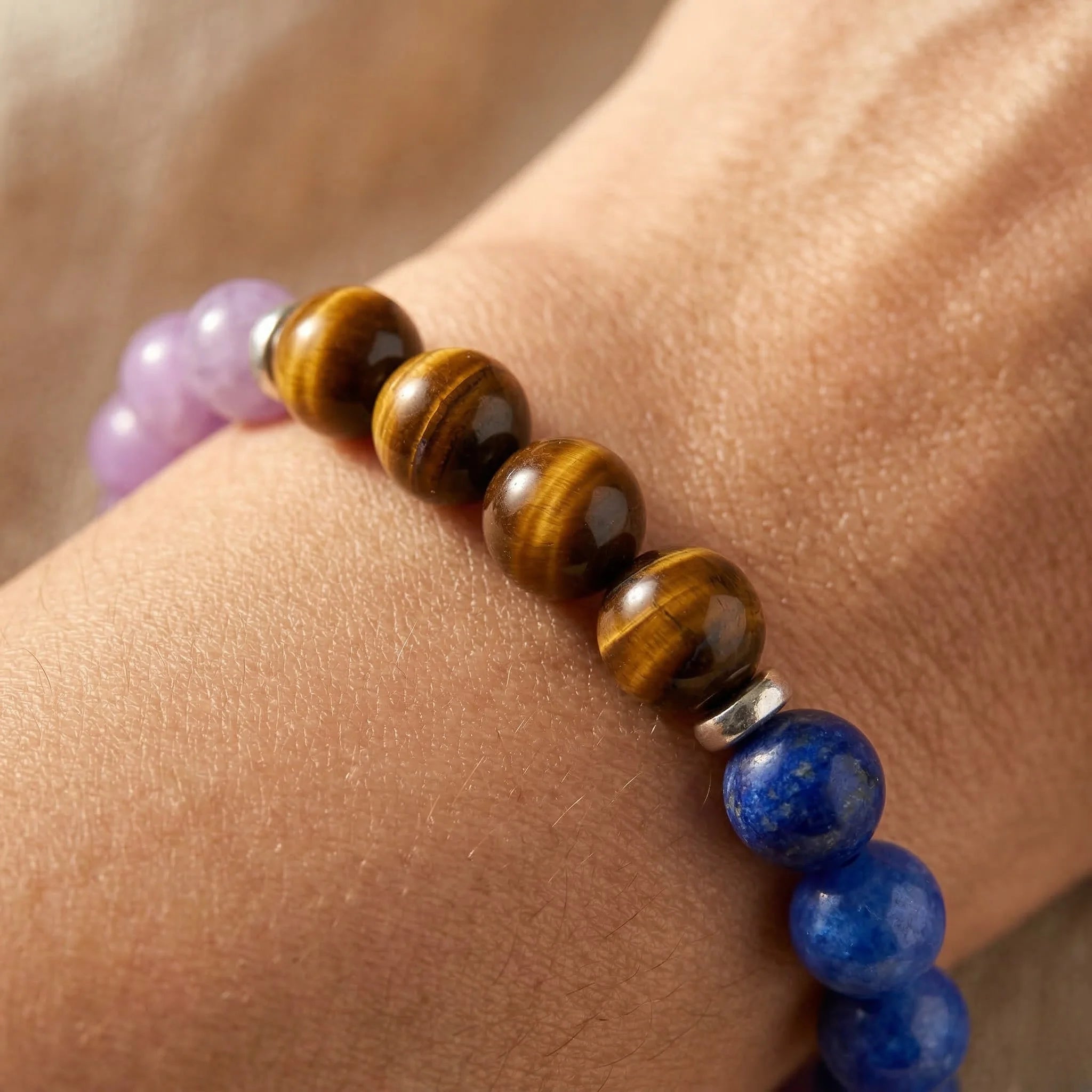 Close-up of a bracelet with brown, purple, and blue beads on a wrist.