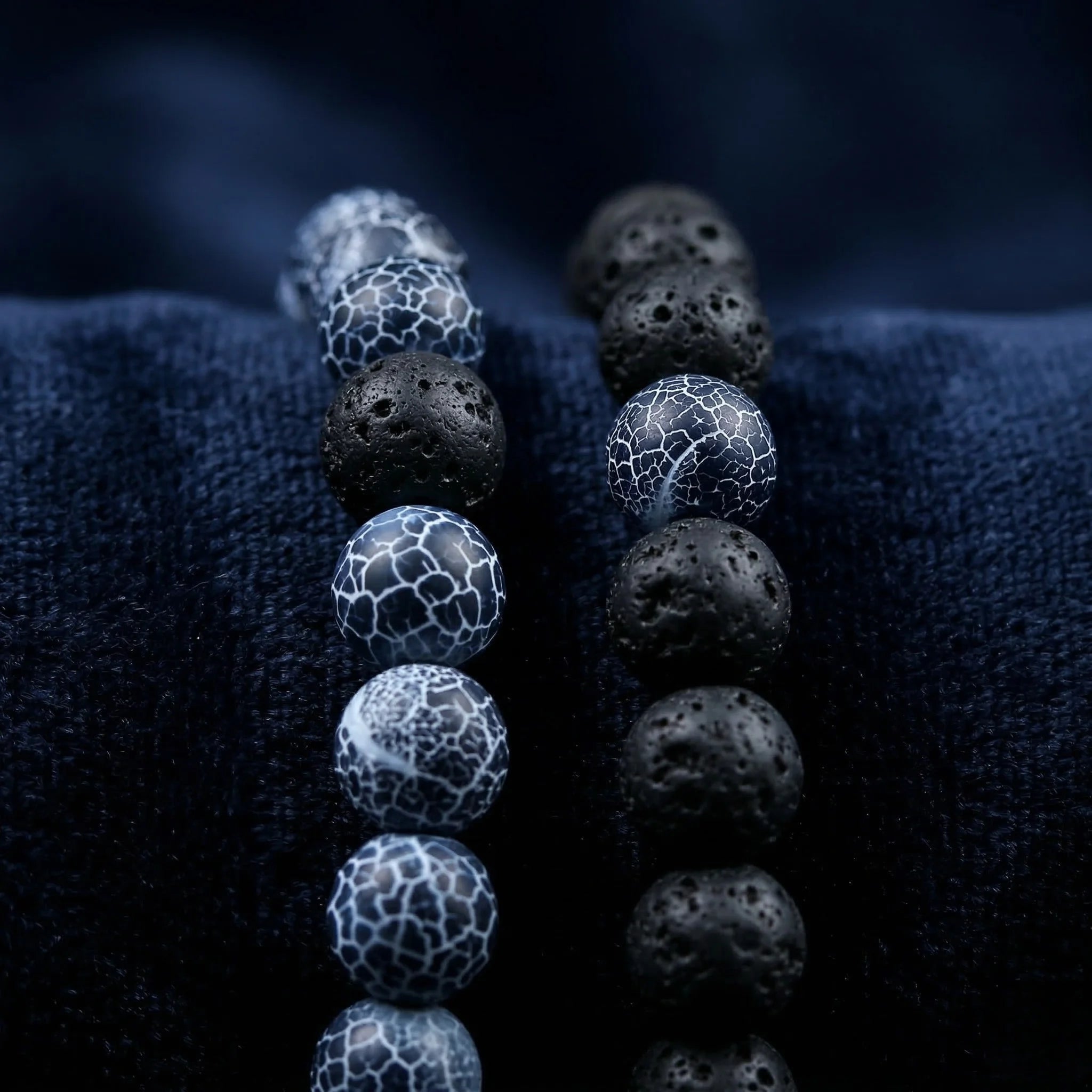 Alternating black and blue spherical beads on a textured dark fabric background