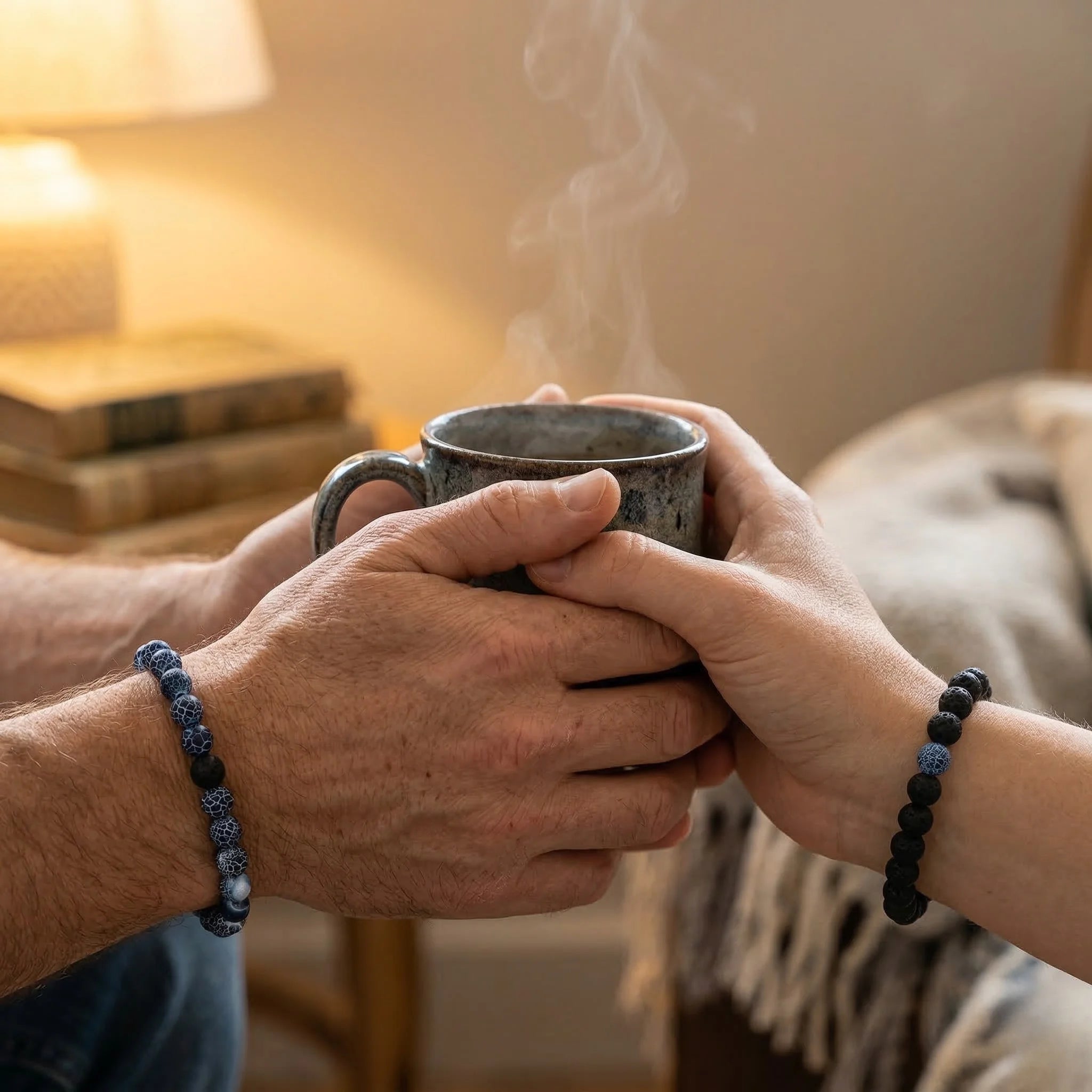 Two pairs of hands holding a steaming mug in a cozy indoor setting.