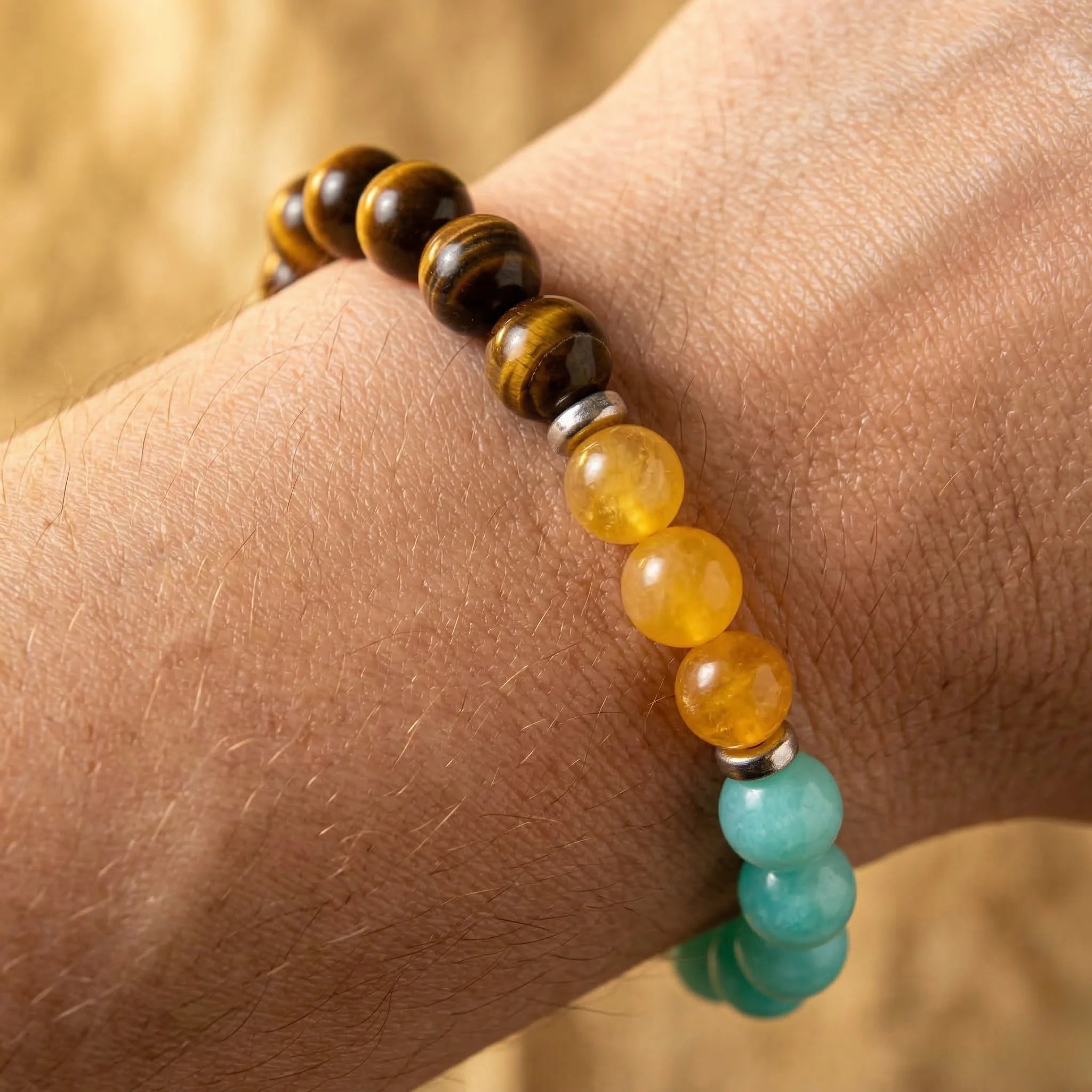 Beaded bracelet with brown, yellow, and turquoise beads on a wrist against a blurred background