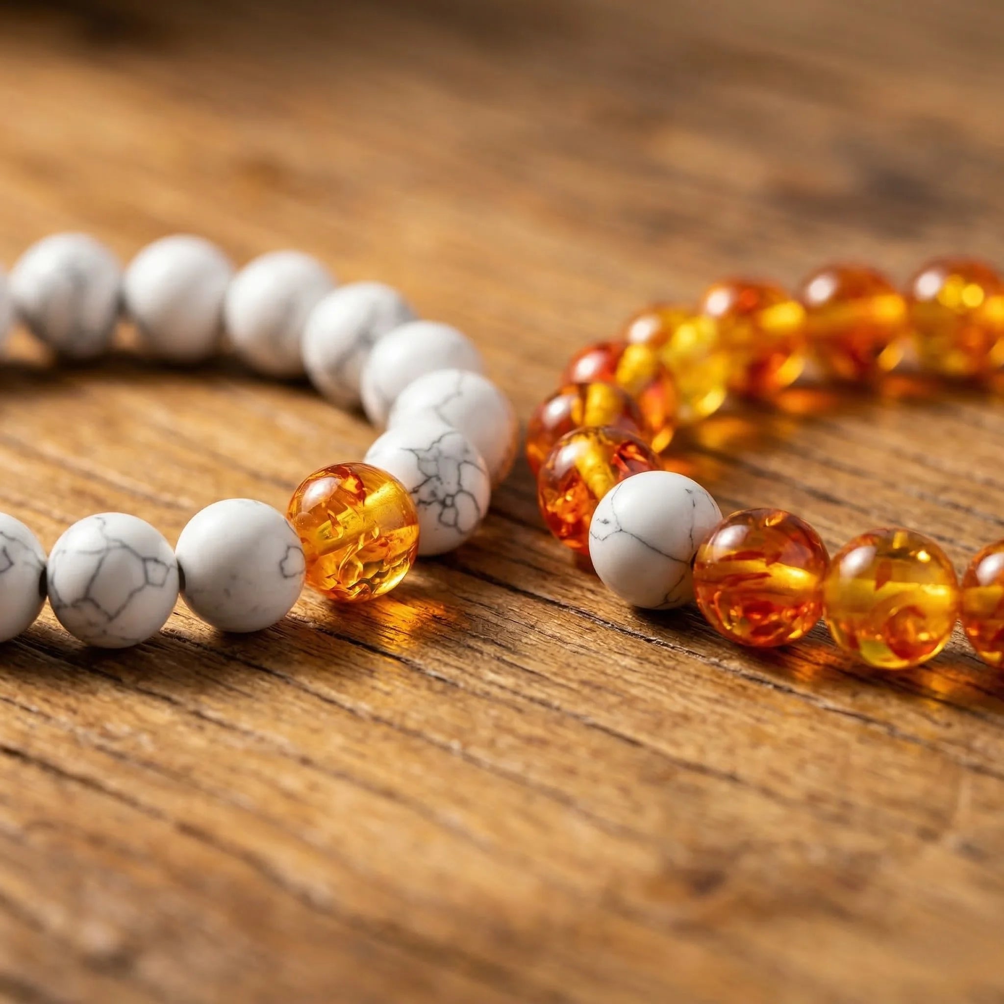 Two beaded bracelets, one with white beads and the other with orange beads, on a wooden surface.