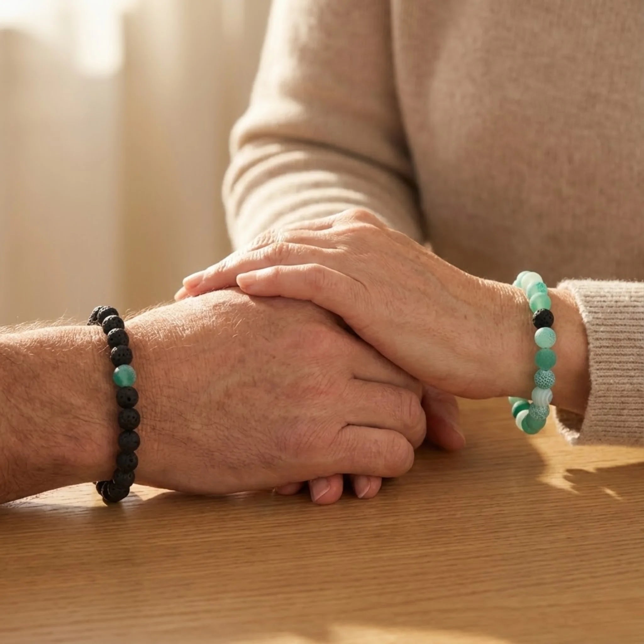 Two people holding hands with bracelets on a wooden surface