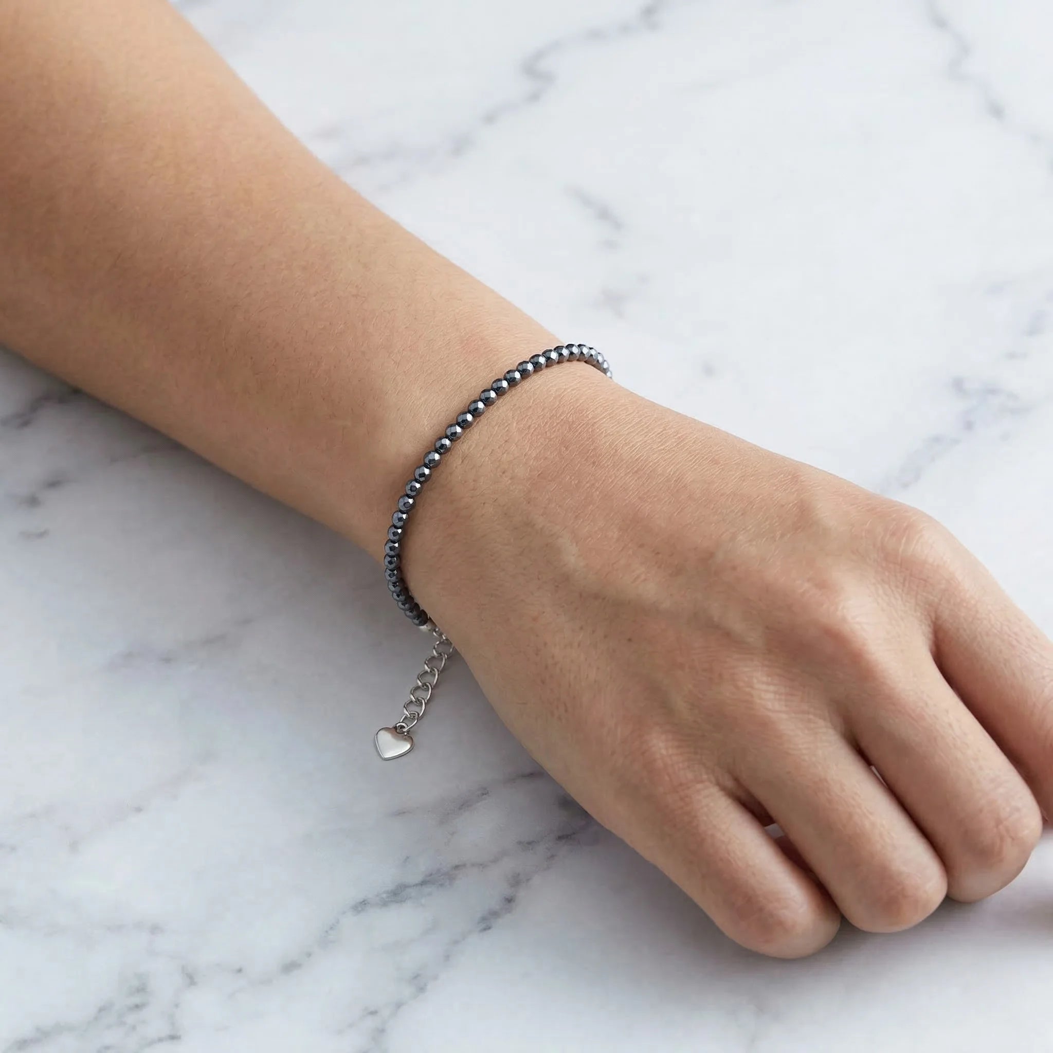 Hand wearing a bracelet on a marble surface