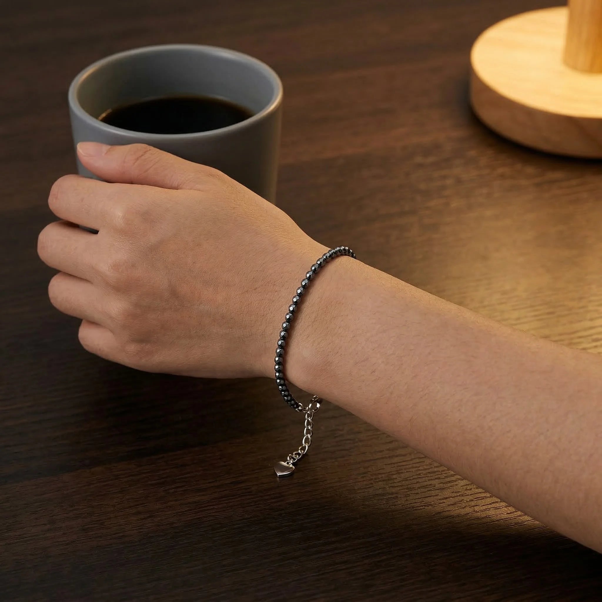 Hand holding a gray mug of coffee on a wooden table