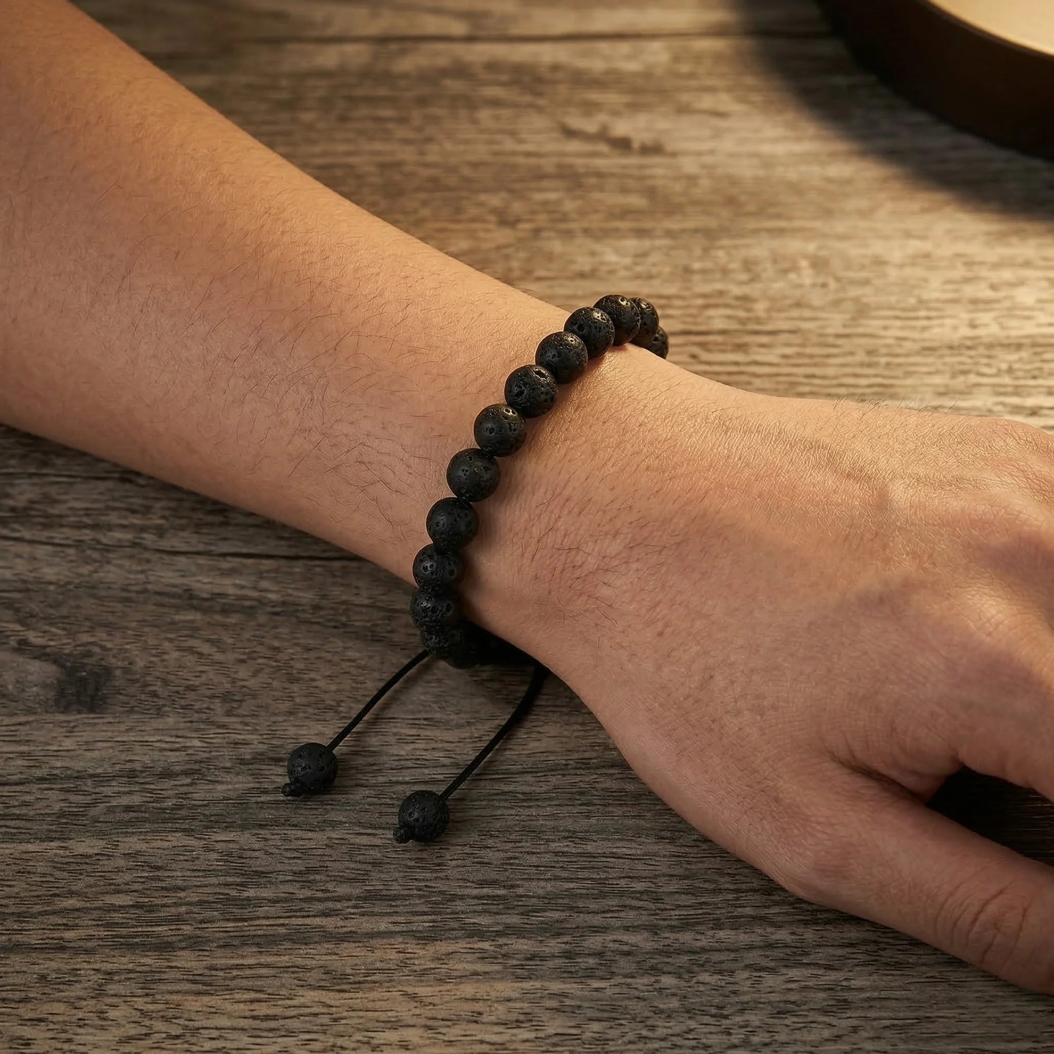 Black beaded bracelet on a wrist against a wooden background