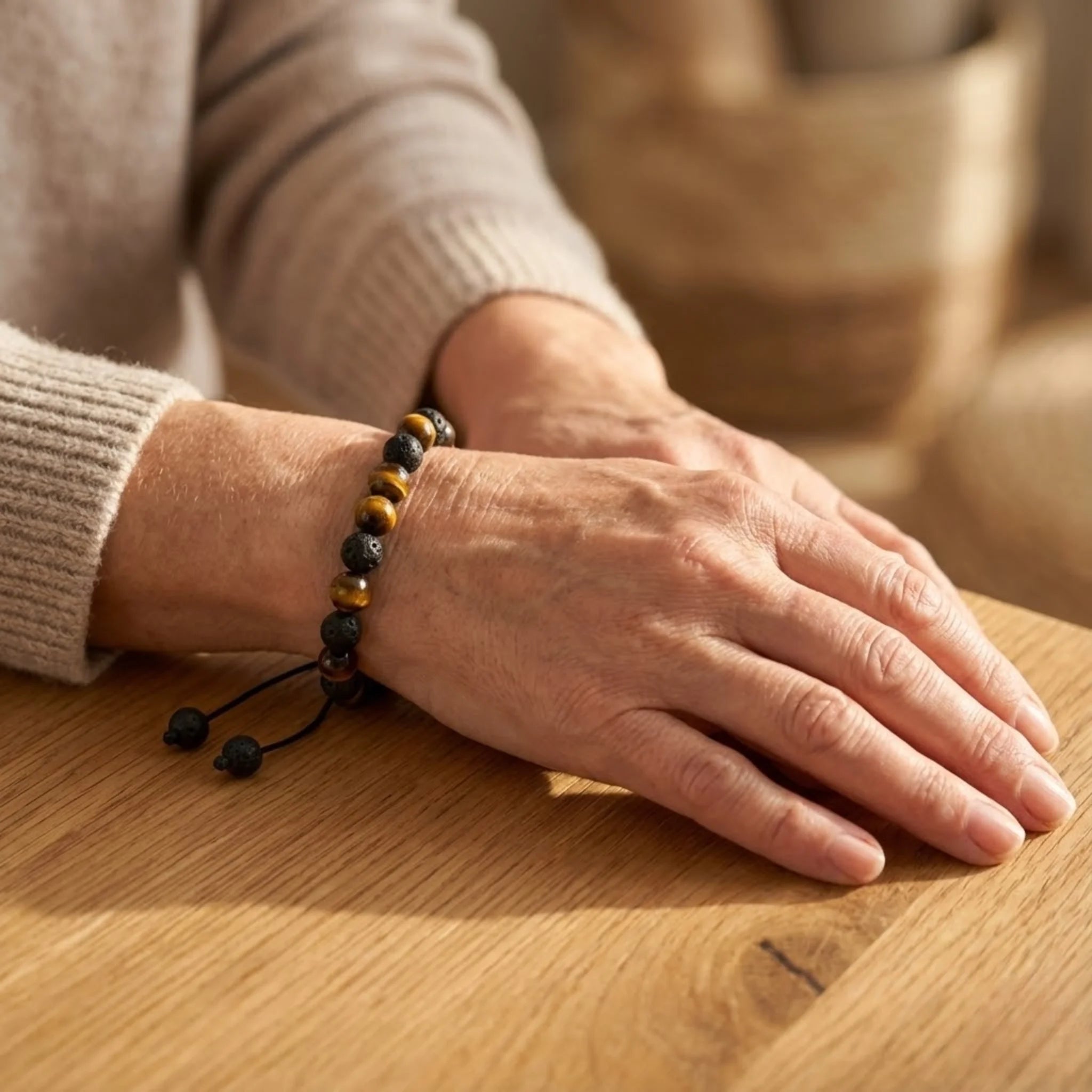 Close-up of a person's hand wearing a black and yellow beaded Adjustable balance bracelet with lava stone and tiger’s eye beads for strength and protection bracelet on a wooden surface.