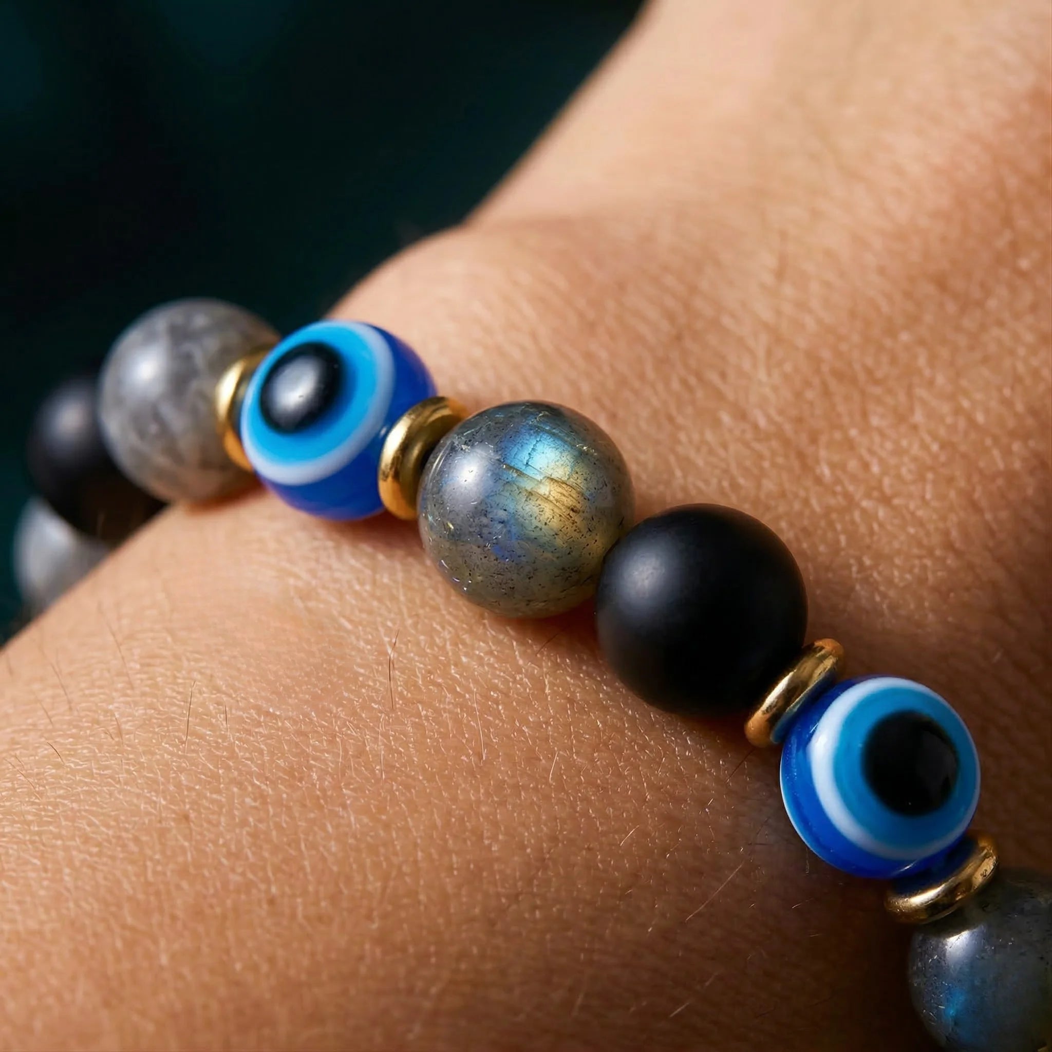 Close-up of a beaded bracelet with blue evil eye beads on a wrist.