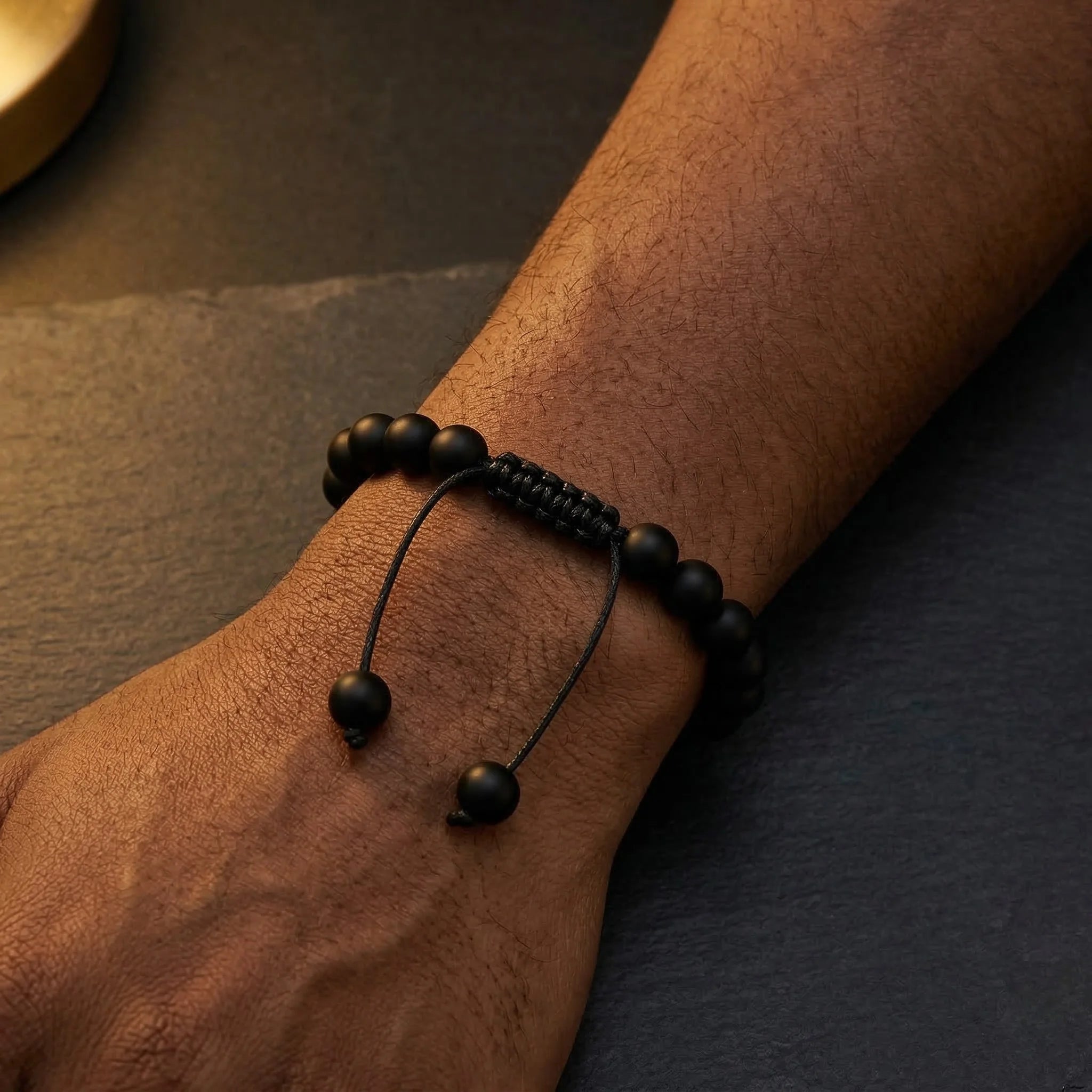 Black beaded bracelet on a wrist with a dark background
