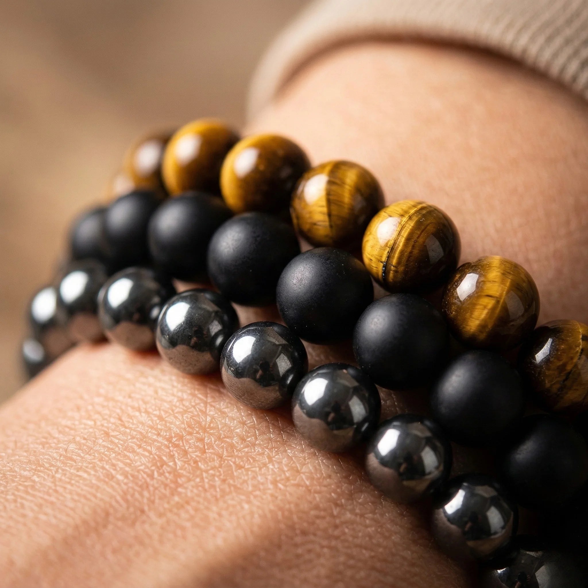 Close-up of a wrist wearing two beaded bracelets with black and brown beads.