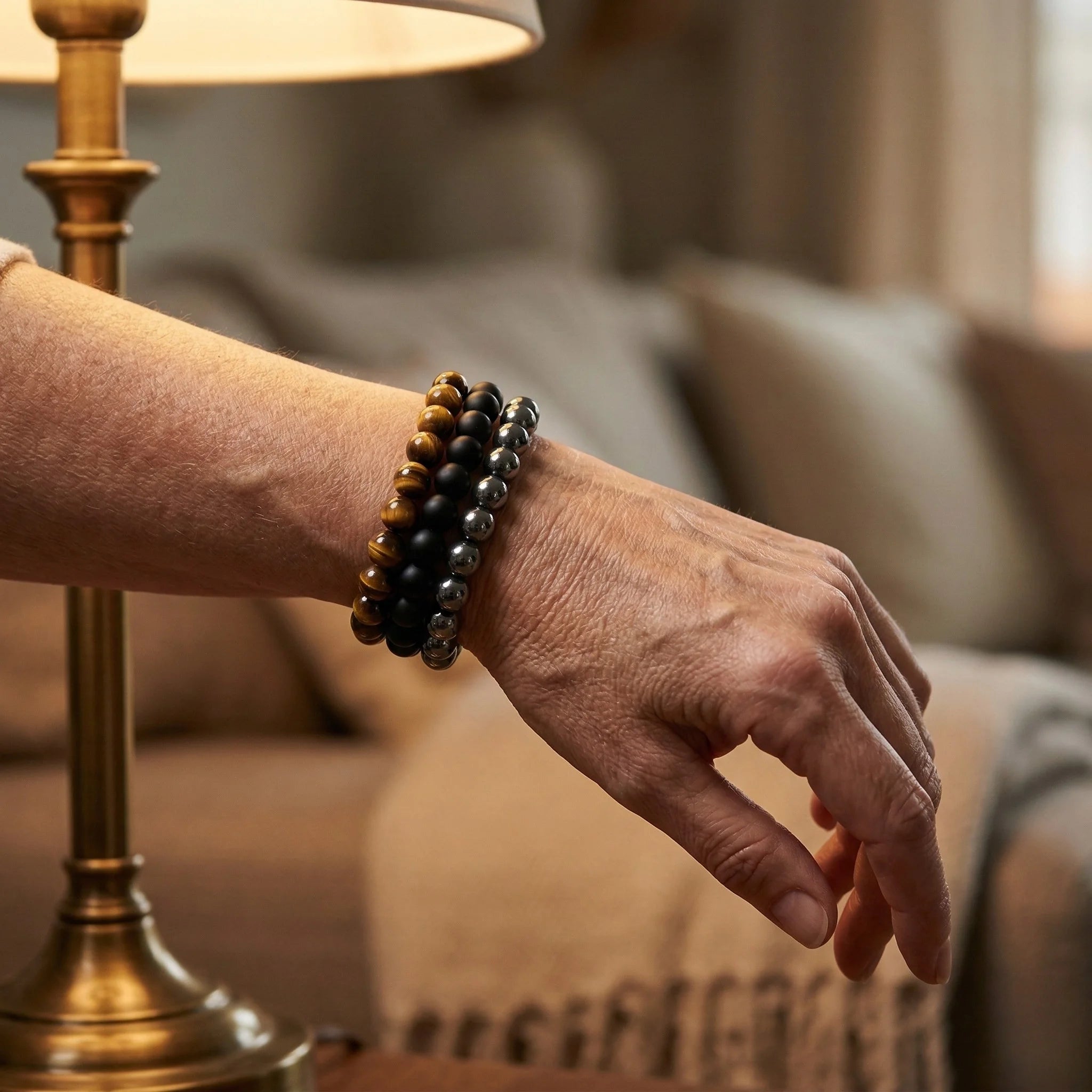 Hand wearing a beaded bracelet with a blurred indoor background