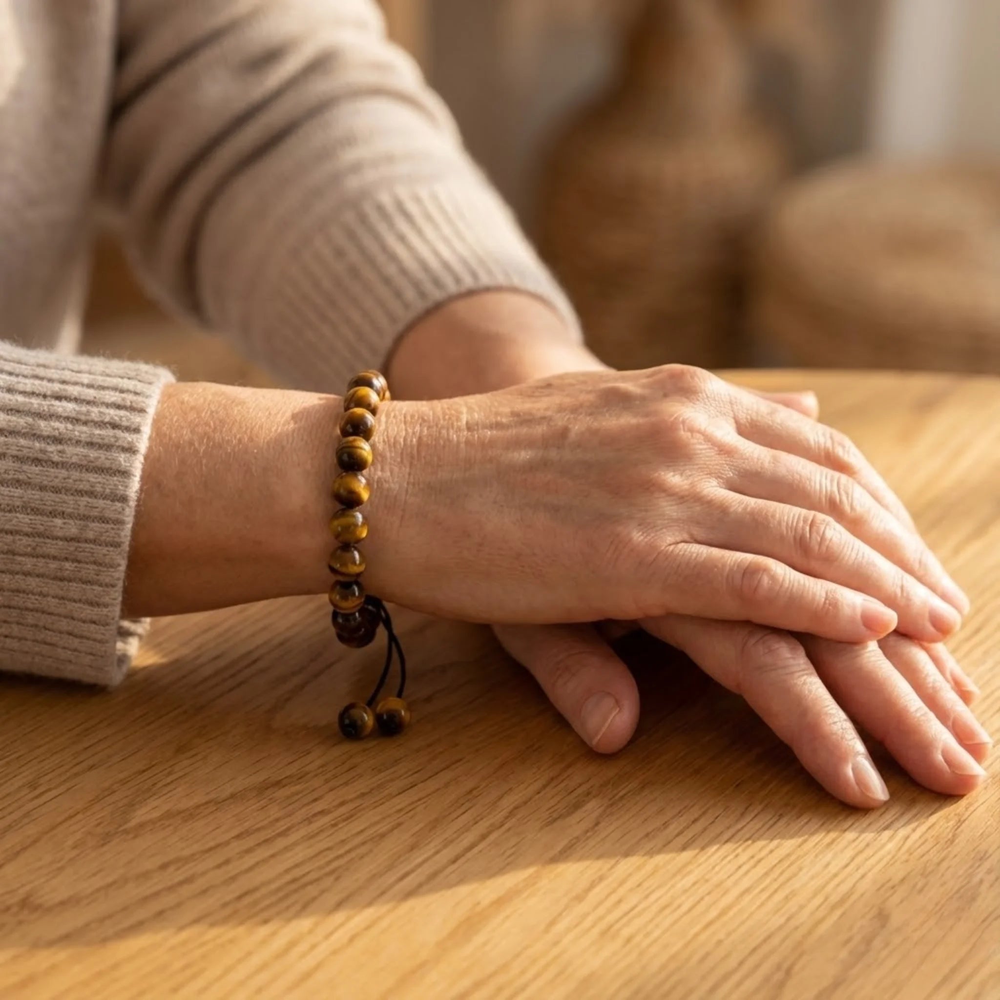 Close-up of hands with a Adjustable balance bracelet crafted with tiger’s eye beads on a braided cord for a classic, earthy look bracelet on a wooden surface