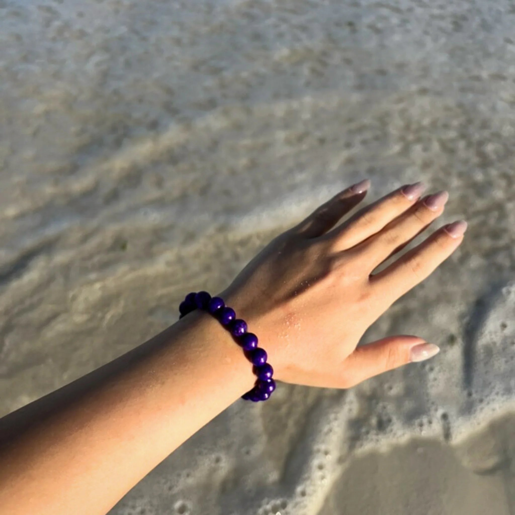 Gemstone4K amethyst bracelet worn on wrist outdoors, showing natural red earthy tone and polished beads.