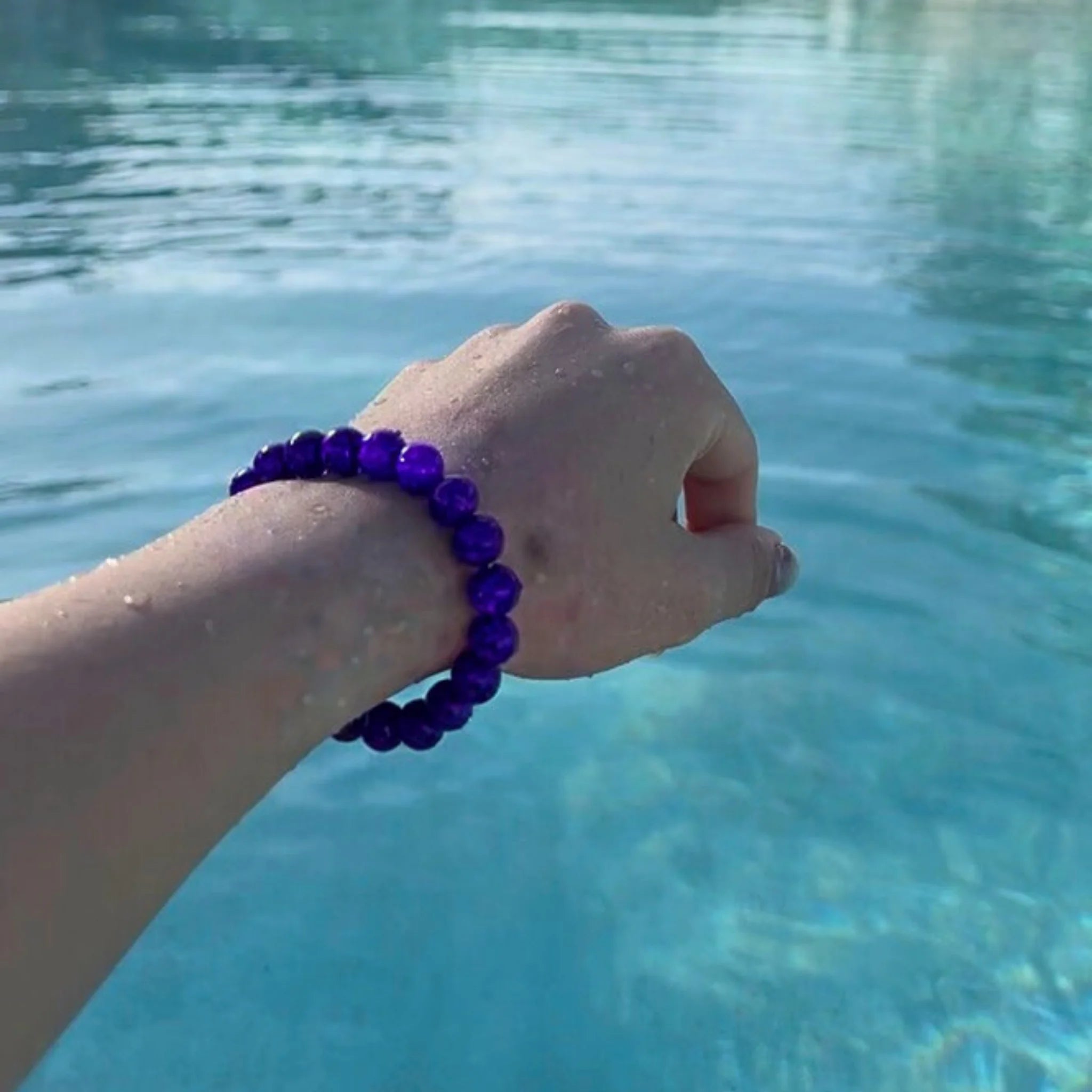 Gemstone4K amethyst bracelet worn on wrist outdoors, showing natural red earthy tone and polished beads.