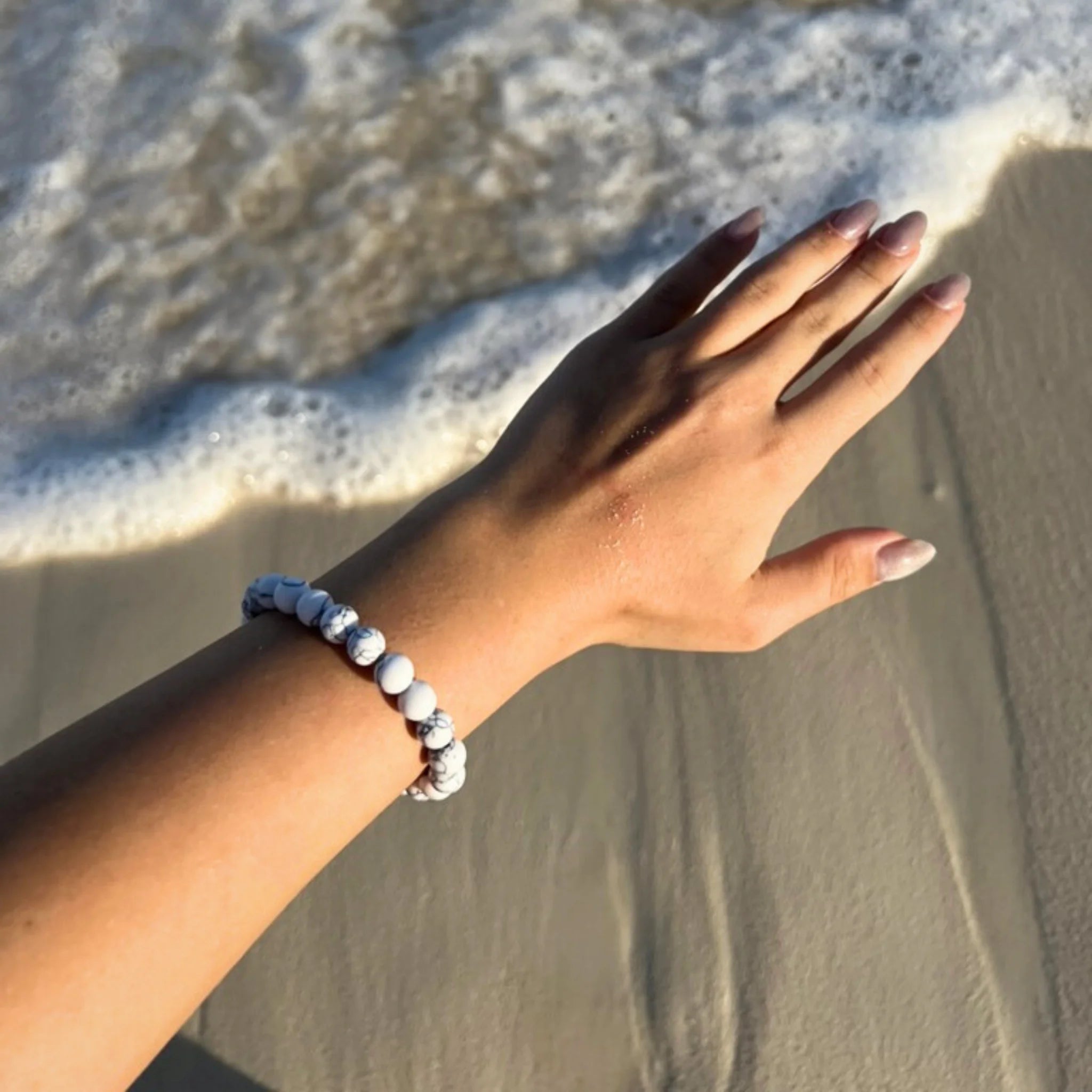 Gemstone4K howlite bracelet worn on wrist, showing white marbled stones symbolizing calm and peace.