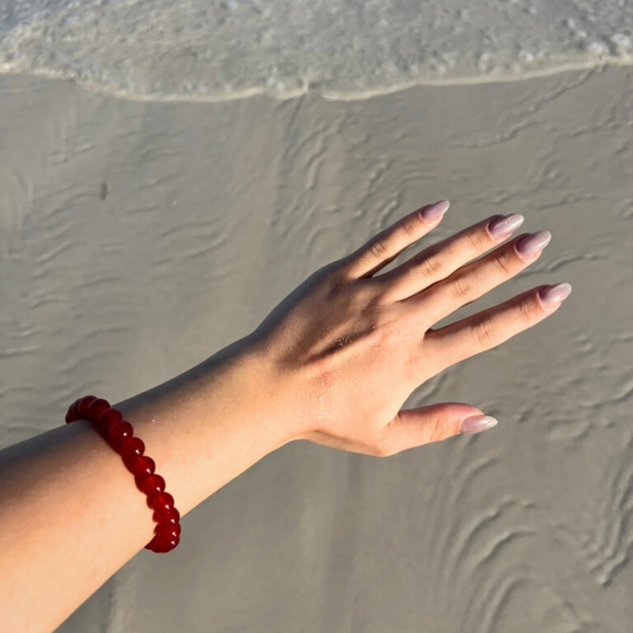 Gemstone4K red jasper bracelet worn on wrist outdoors, showing natural red earthy tone and polished beads.