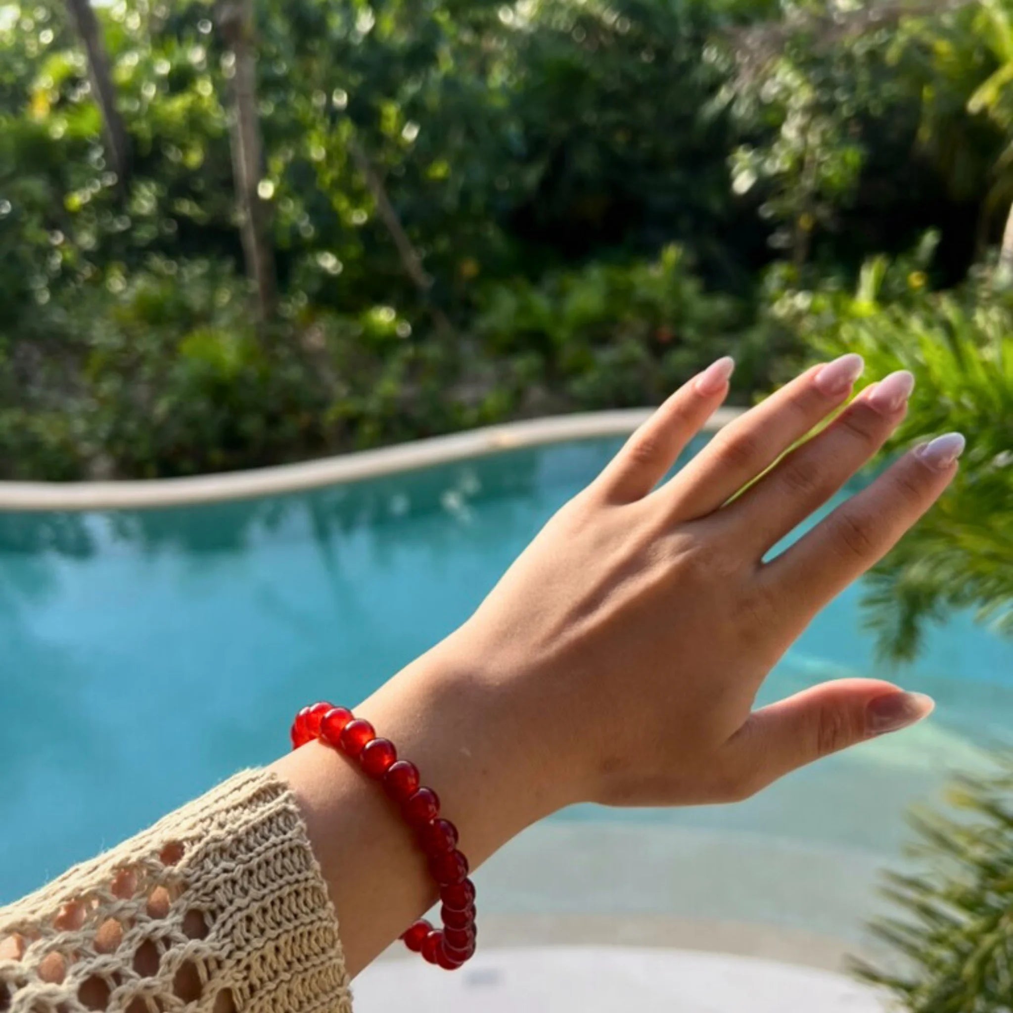 Gemstone4K red jasper bracelet worn on wrist outdoors, showing natural red earthy tone and polished beads.
