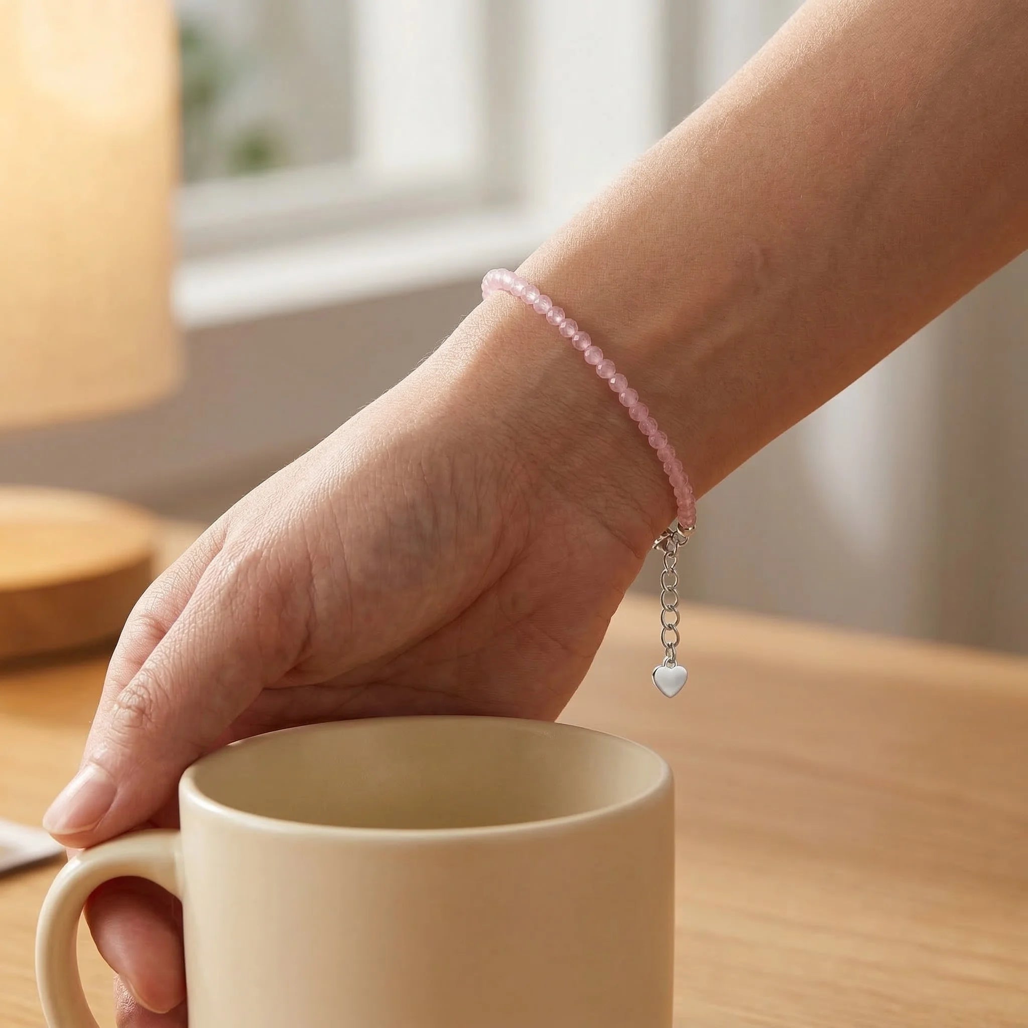 Hand holding a beige mug with a blurred indoor background