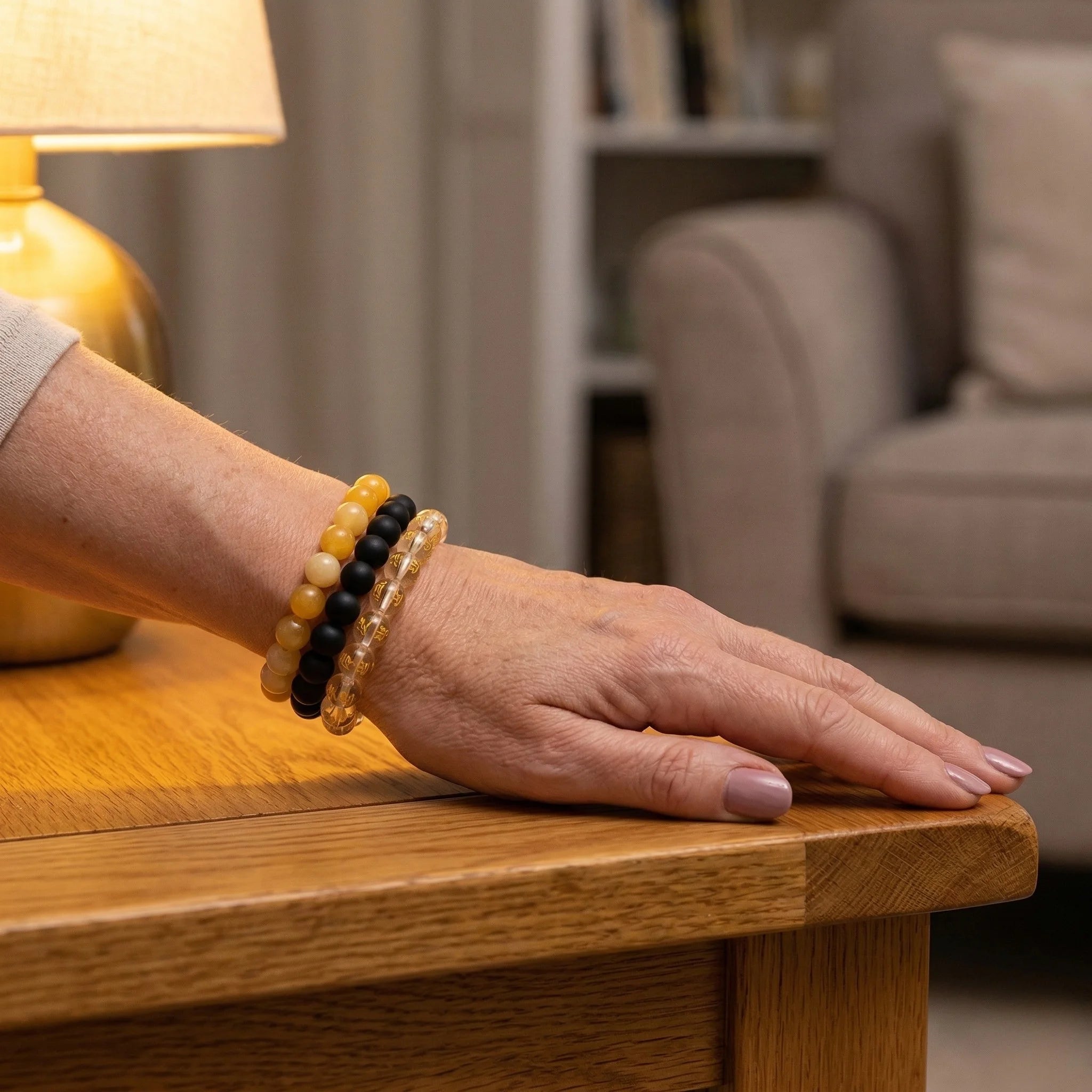 Hand wearing a bracelet on a wooden surface with a blurred background