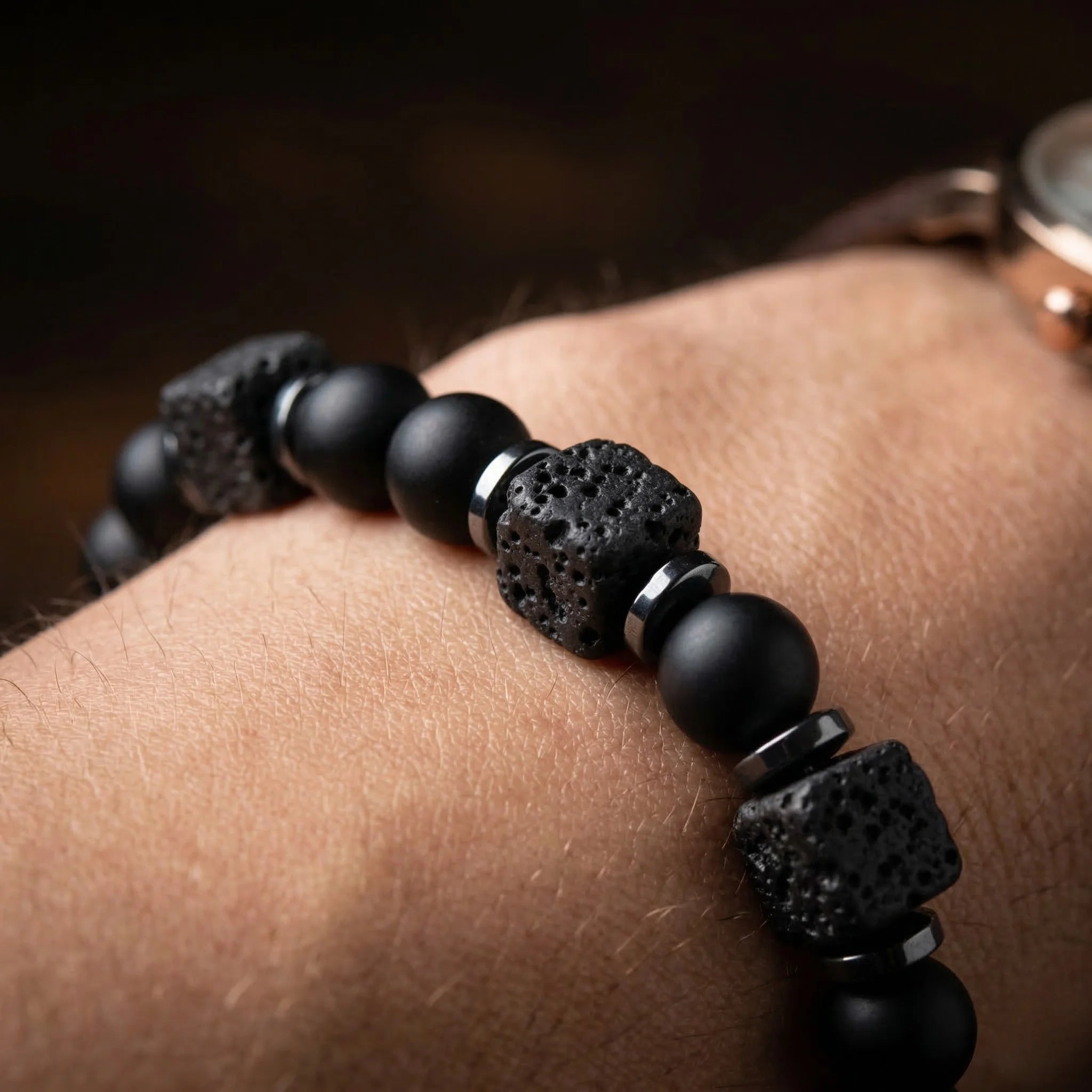 Black beaded bracelet on a wrist with a blurred background