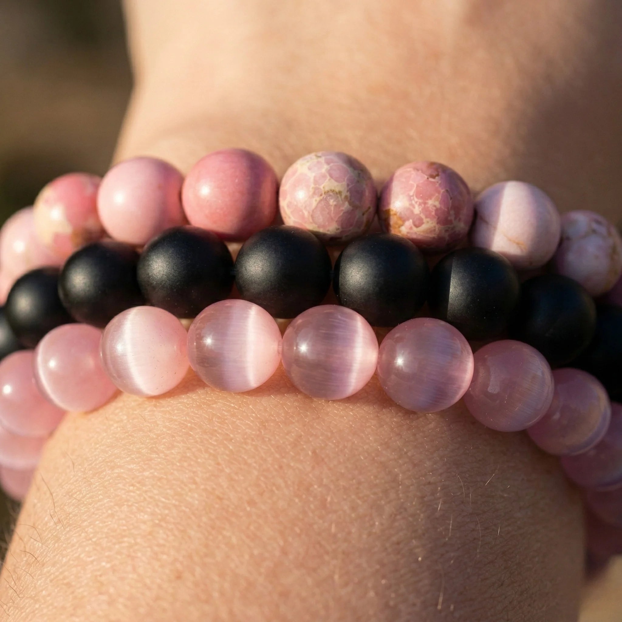Close-up of a bracelet with pink and black beads on a wrist.