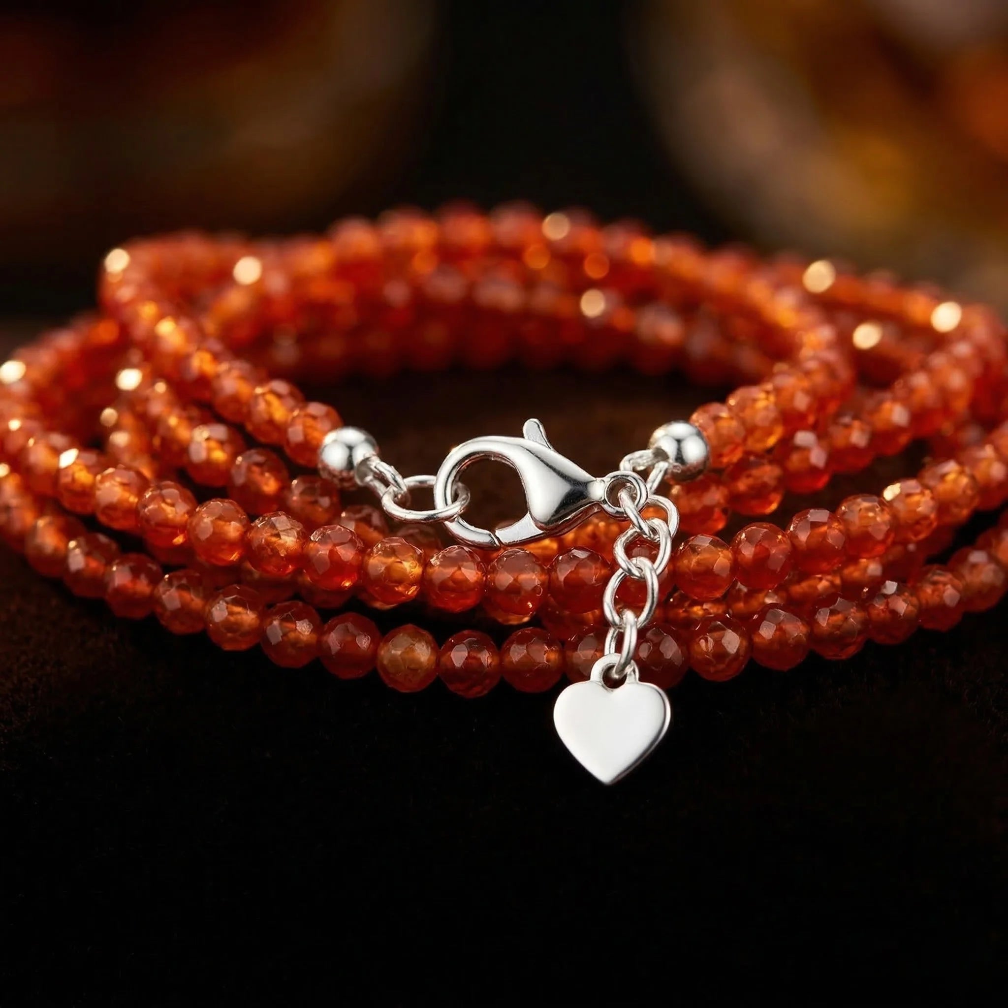 Red beaded bracelet with a silver clasp and heart charm on a dark background