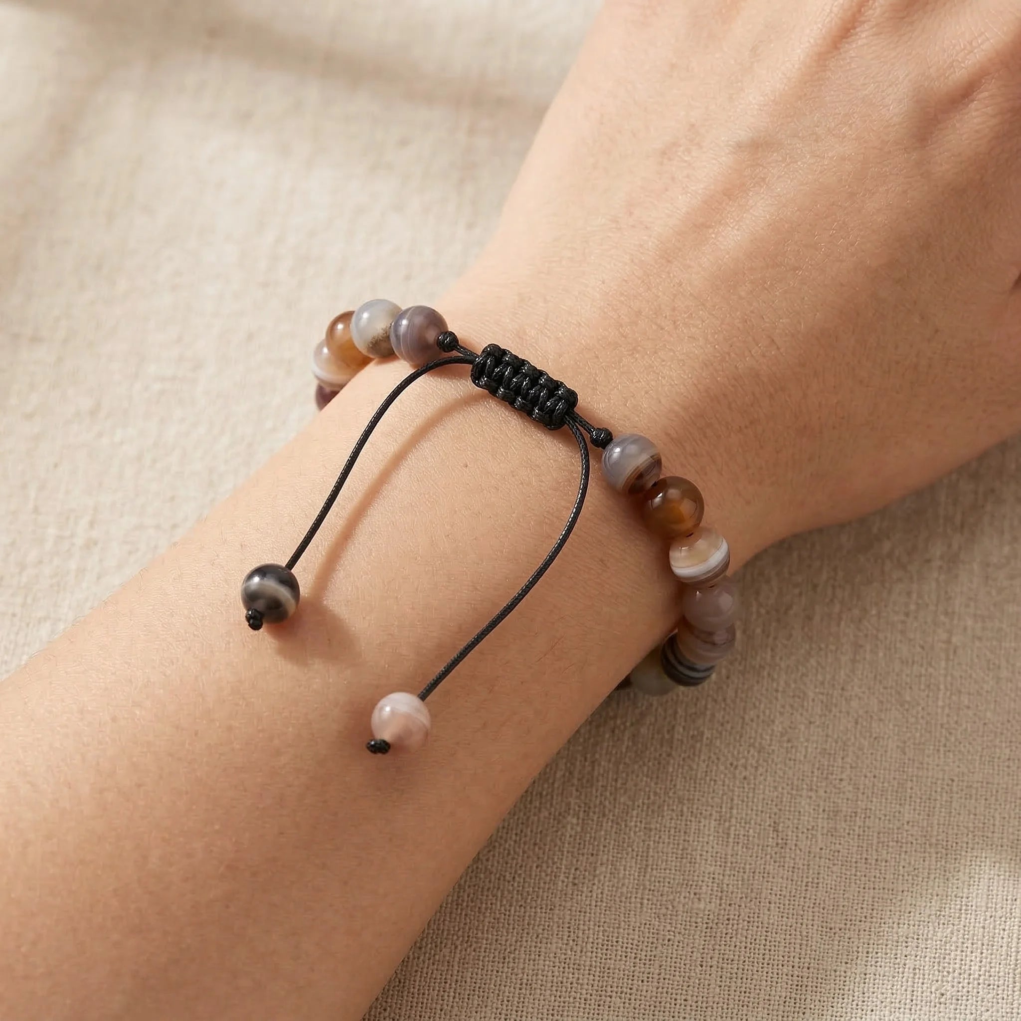 Bracelet with beads on a wrist against a beige background