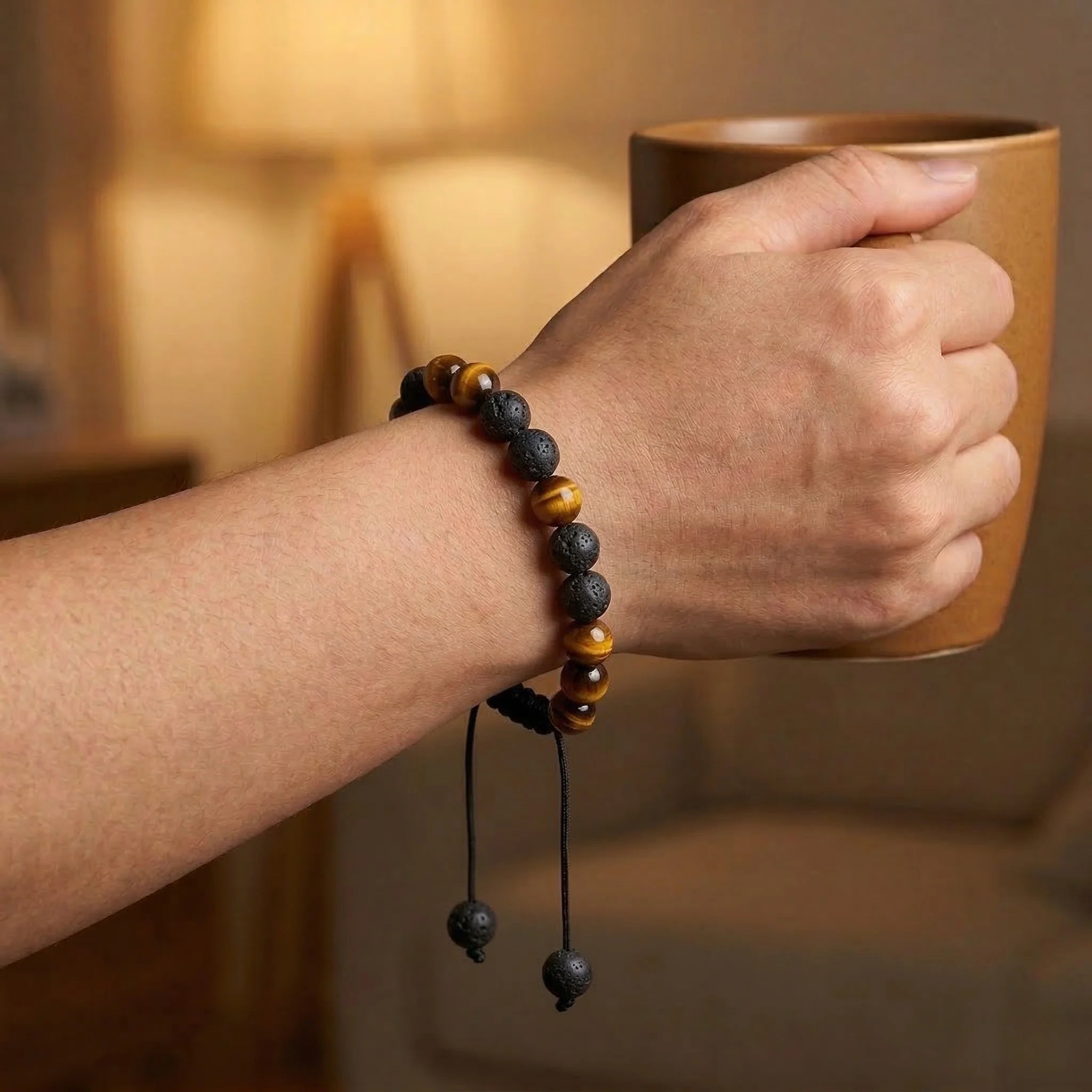 Hand holding a mug with a beaded bracelet on a blurred background