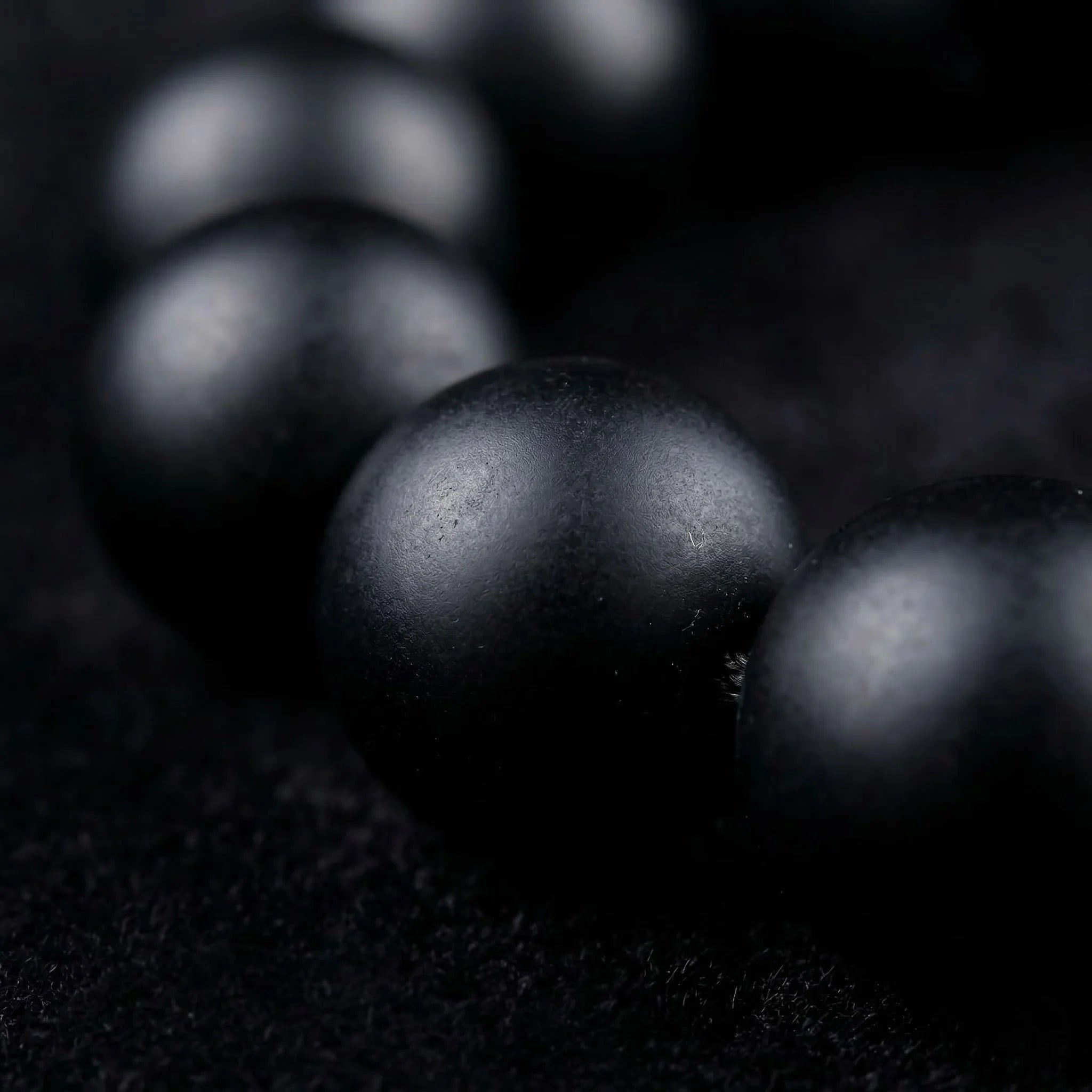 Close-up of black pearls on a dark textured surface