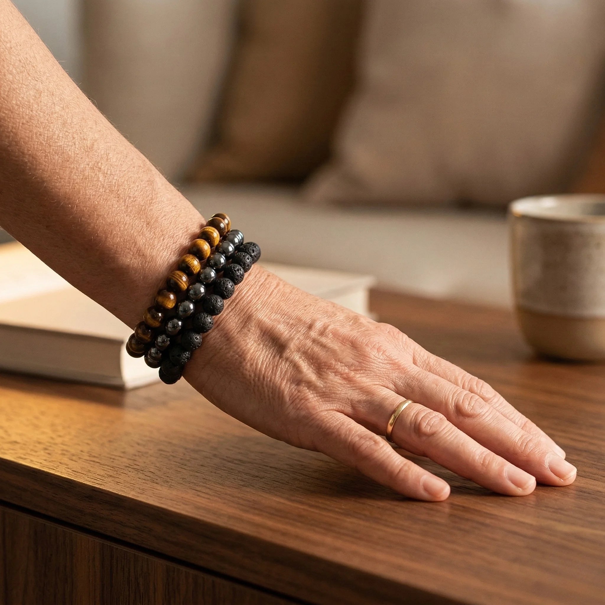 Hand wearing a beaded bracelet on a wooden surface with a blurred background