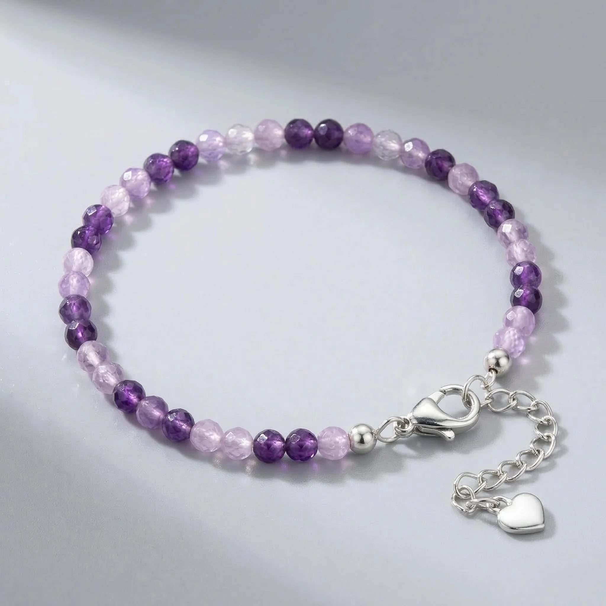 Purple beaded bracelet with a silver clasp on a gray background