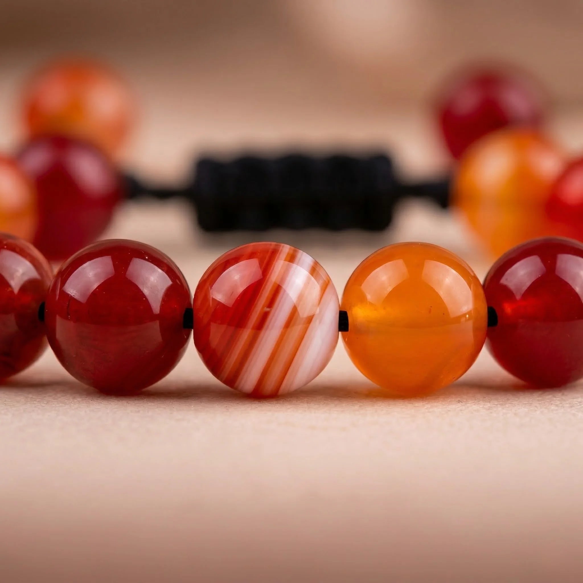Close-up of a bracelet with red and orange beads on a neutral background