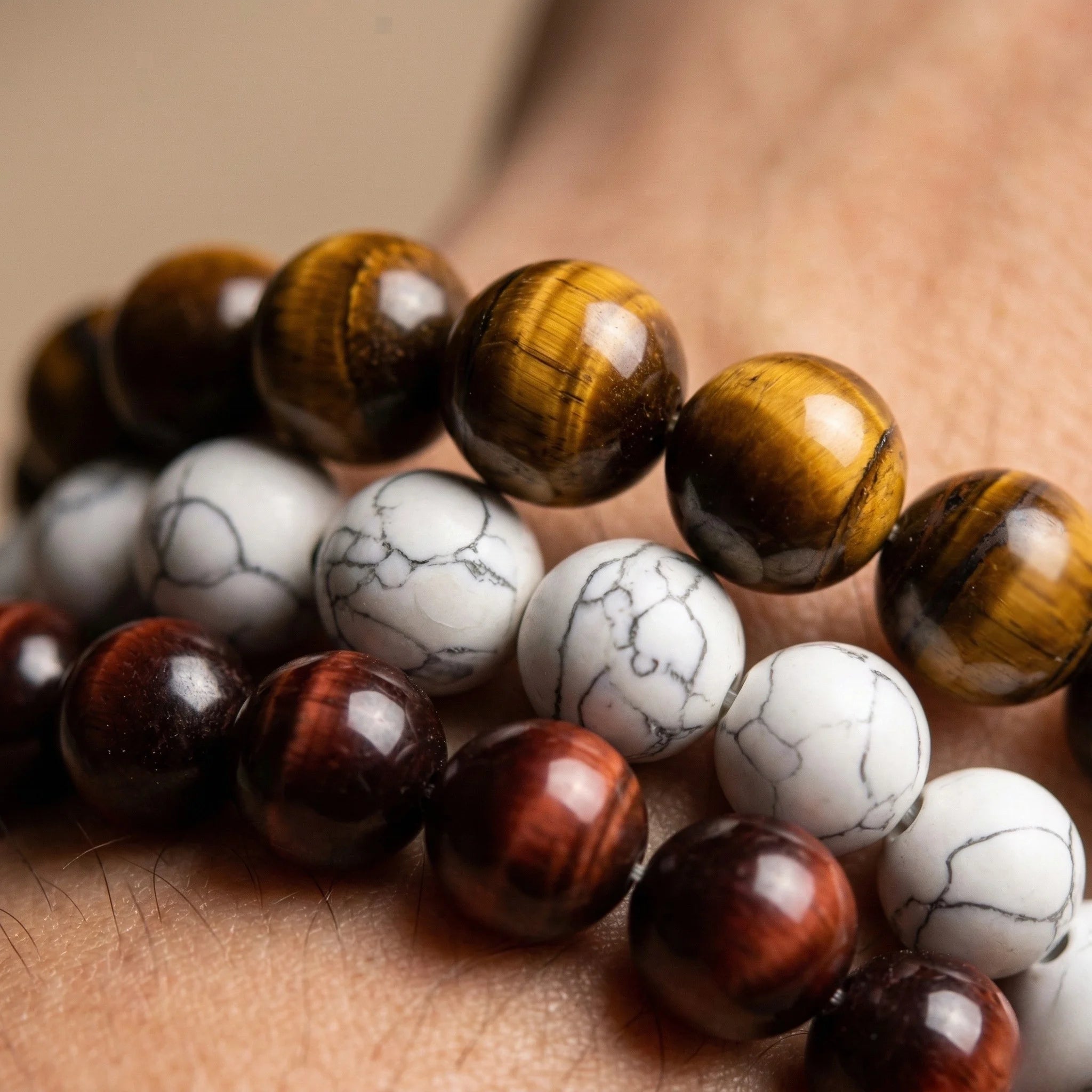 Close-up of a bracelet with tiger eye and howlite beads on skin.