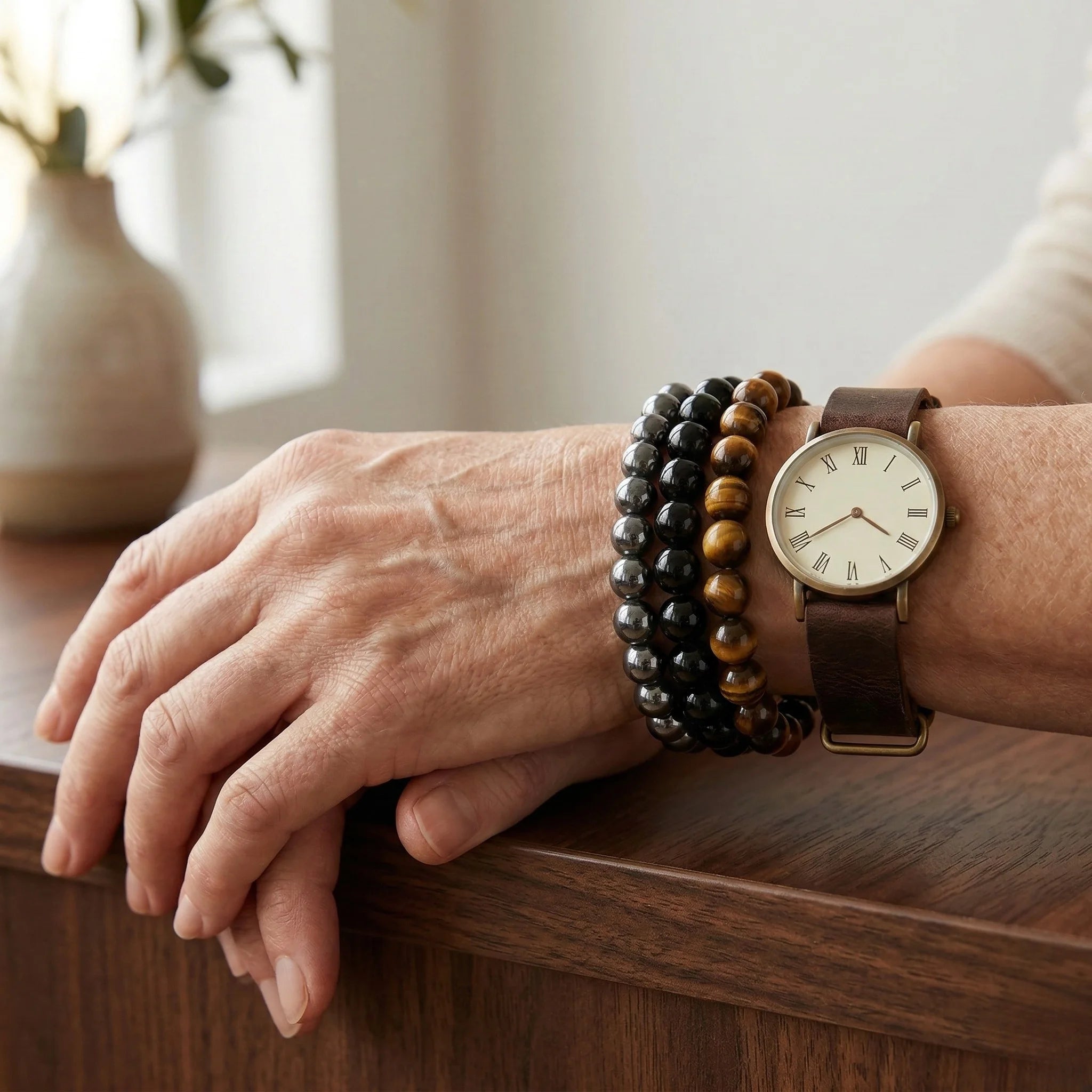 Person's wrist with a watch and bracelets on a wooden surface