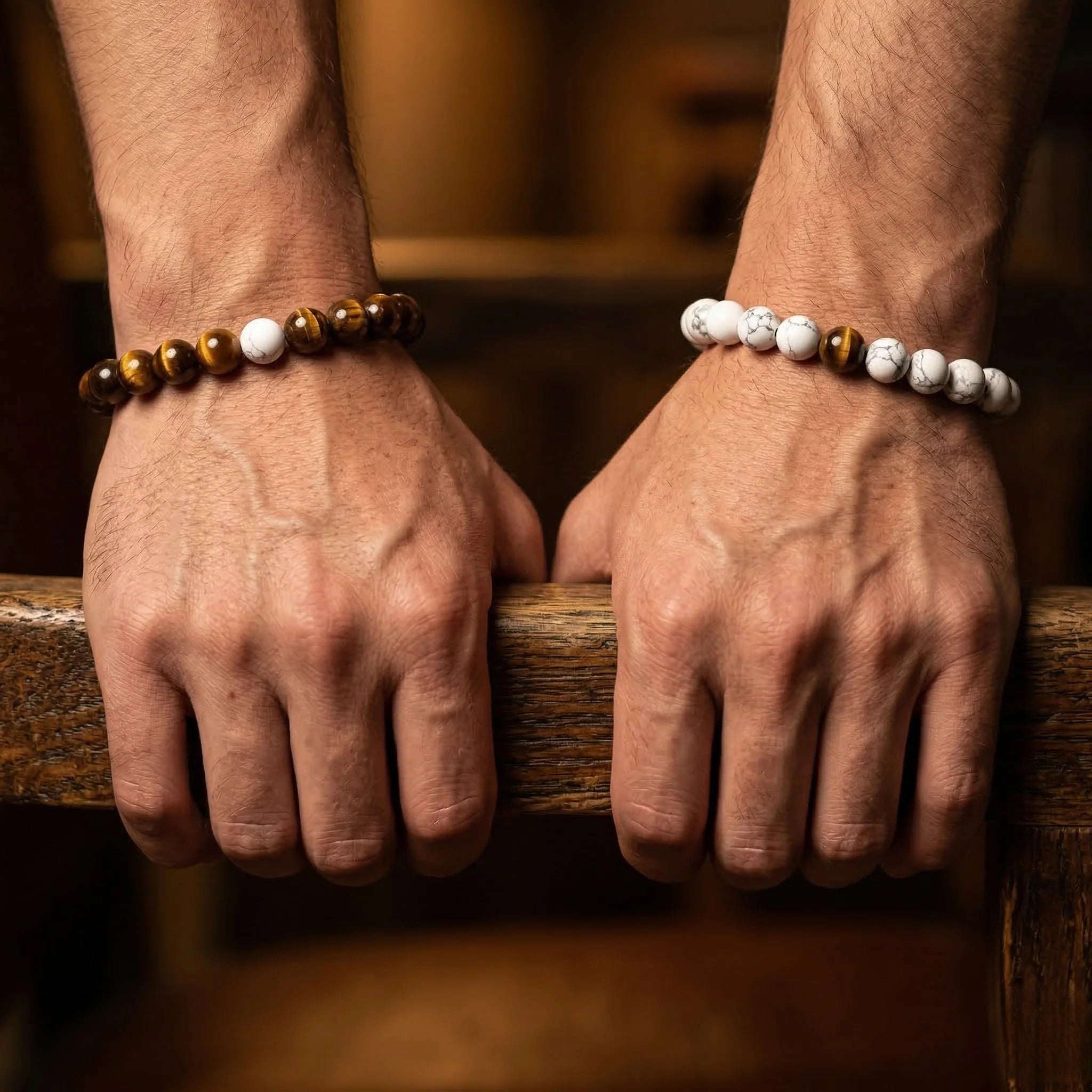 Close-up of two hands wearing beaded bracelets on a wooden surface.