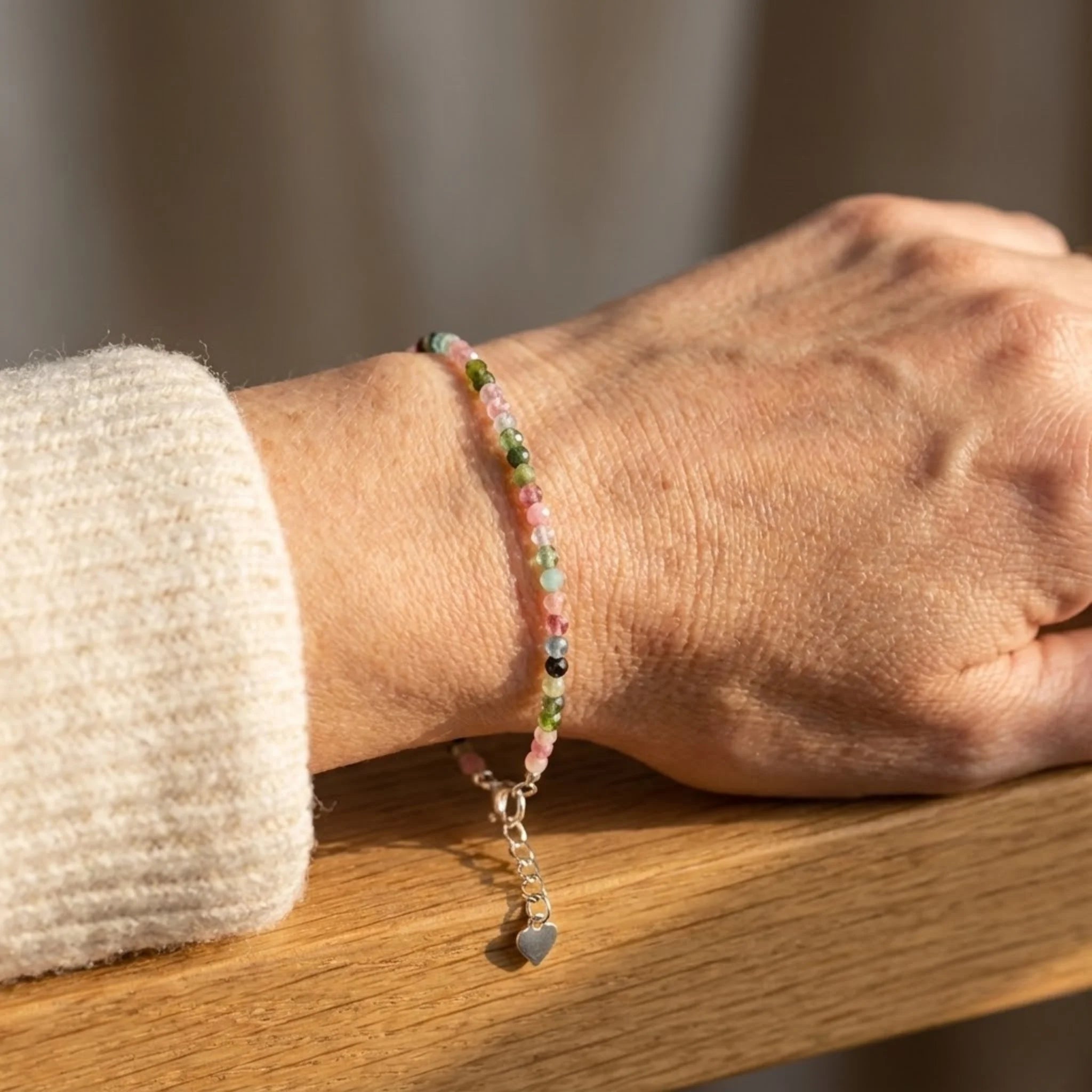 Close-up of a wrist wearing a beaded Essential silver bracelet crafted with tourmaline gemstone beads for a grounded, minimalist style bracelet on a wooden surface