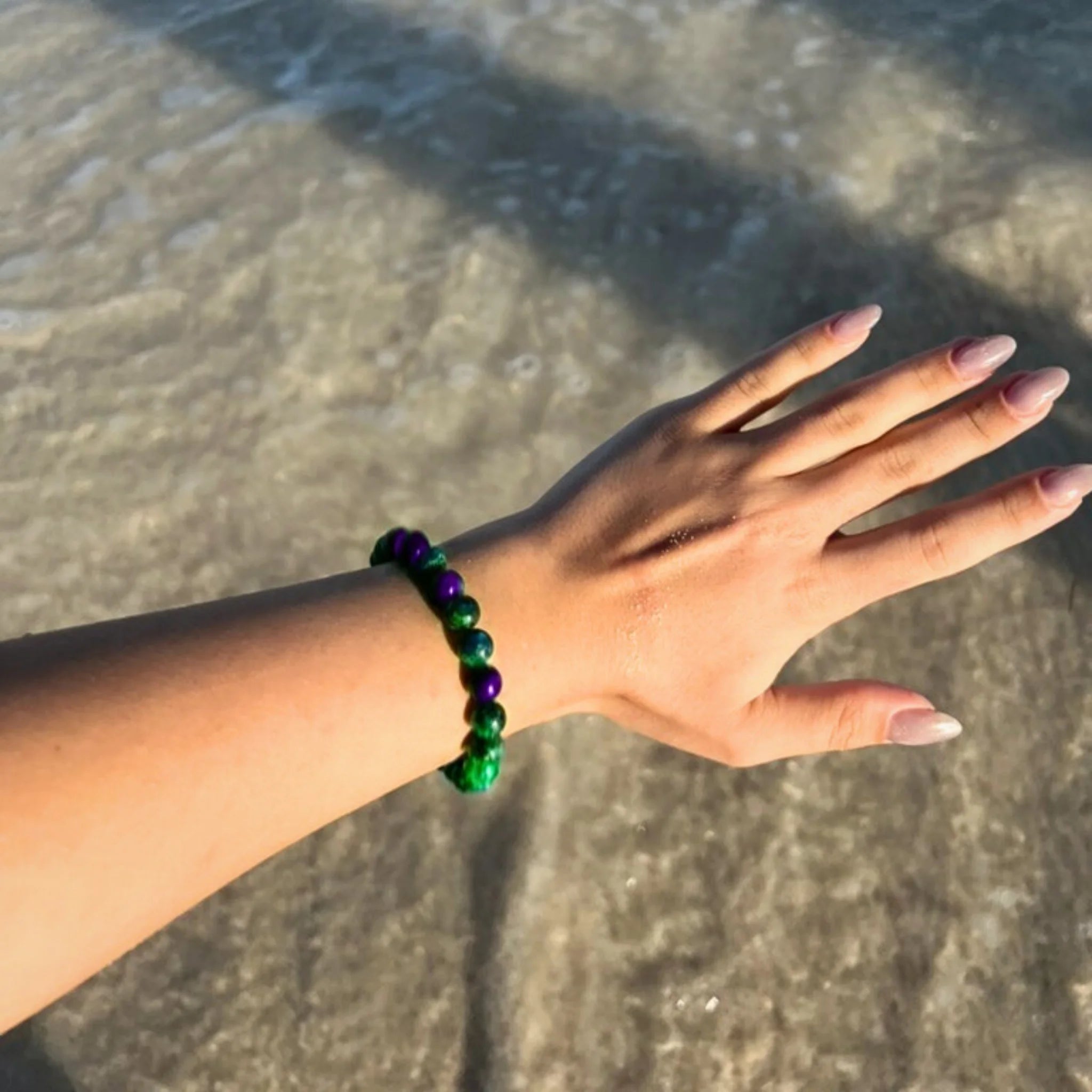 Gemstone4K fluorite bracelet worn on wrist outdoors, showing translucent lavender and green tones.