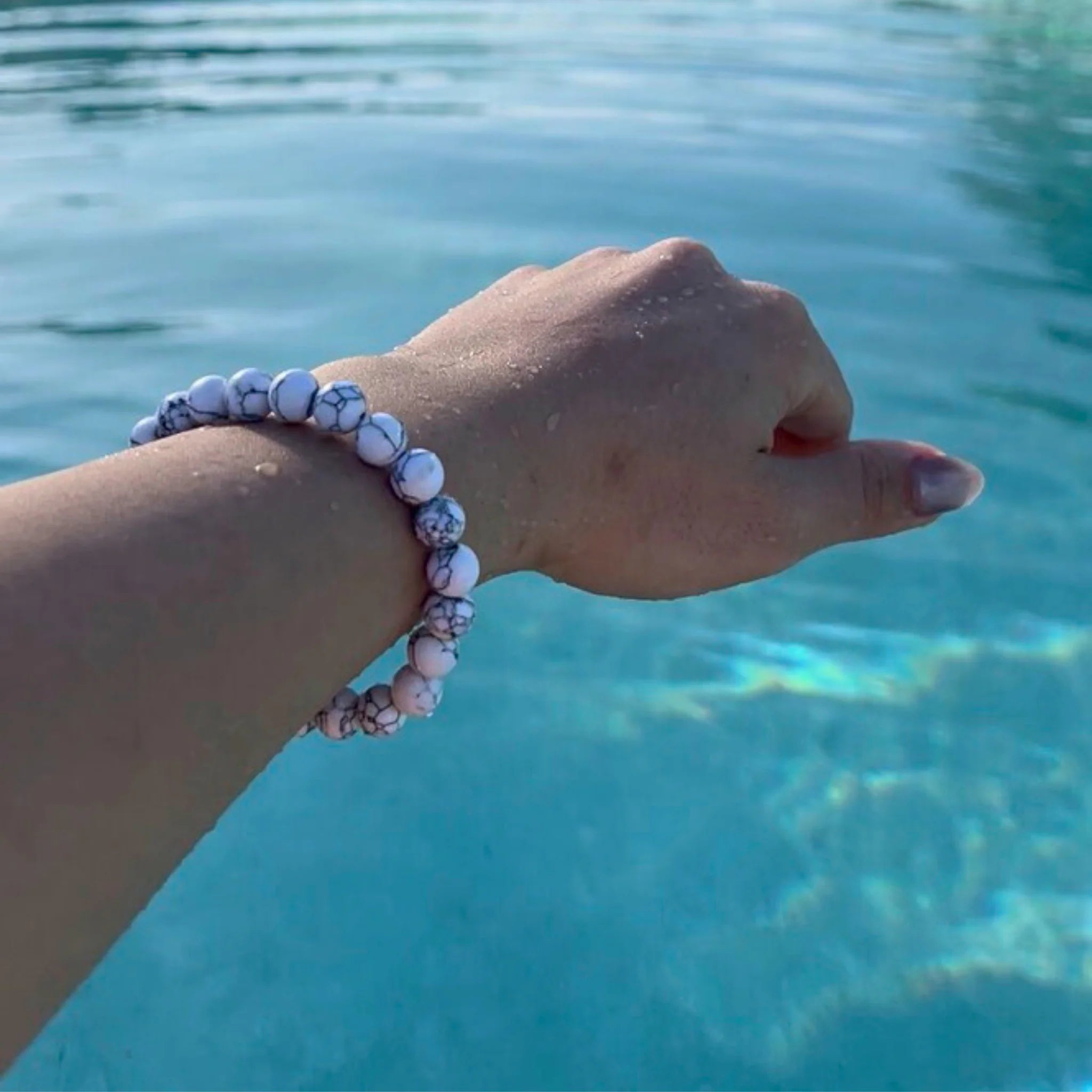 Gemstone4K howlite bracelet worn on wrist, showing white marbled stones symbolizing calm and peace.