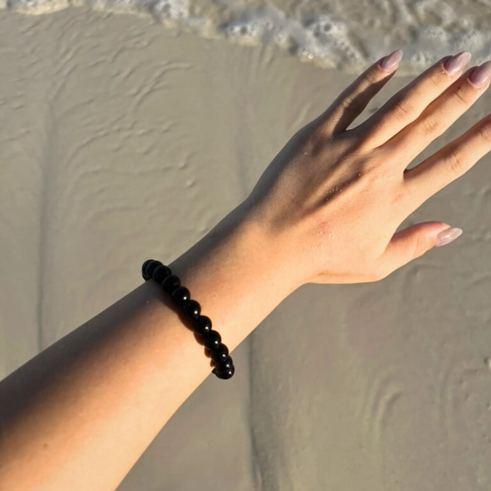 Gemstone4K onyx bracelet worn on wrist, showing deep black polished stones with a sleek appearance.
