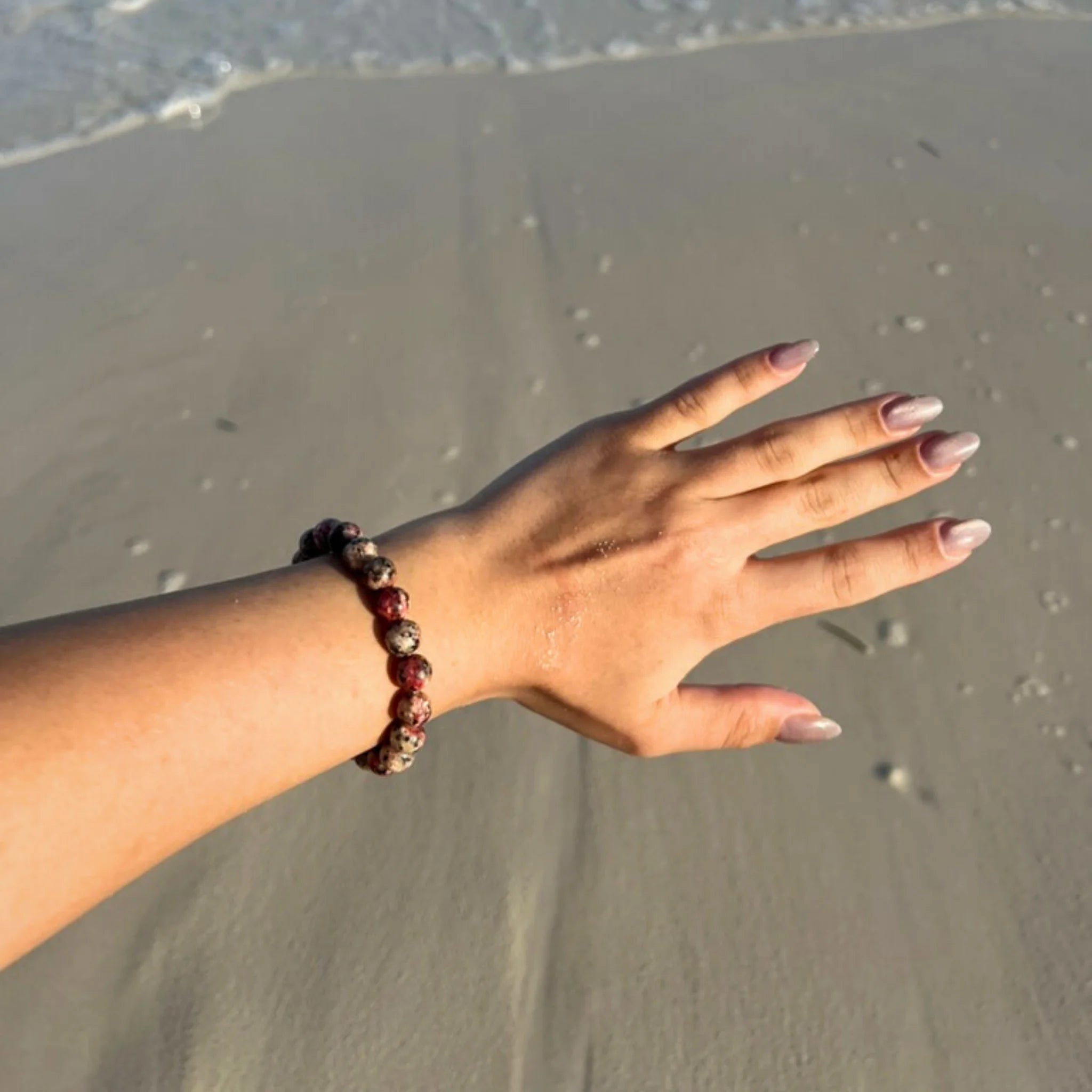 Gemstone4K red leopard skin jasper bracelet worn on wrist outdoors, showing natural patterns and warm red tone.