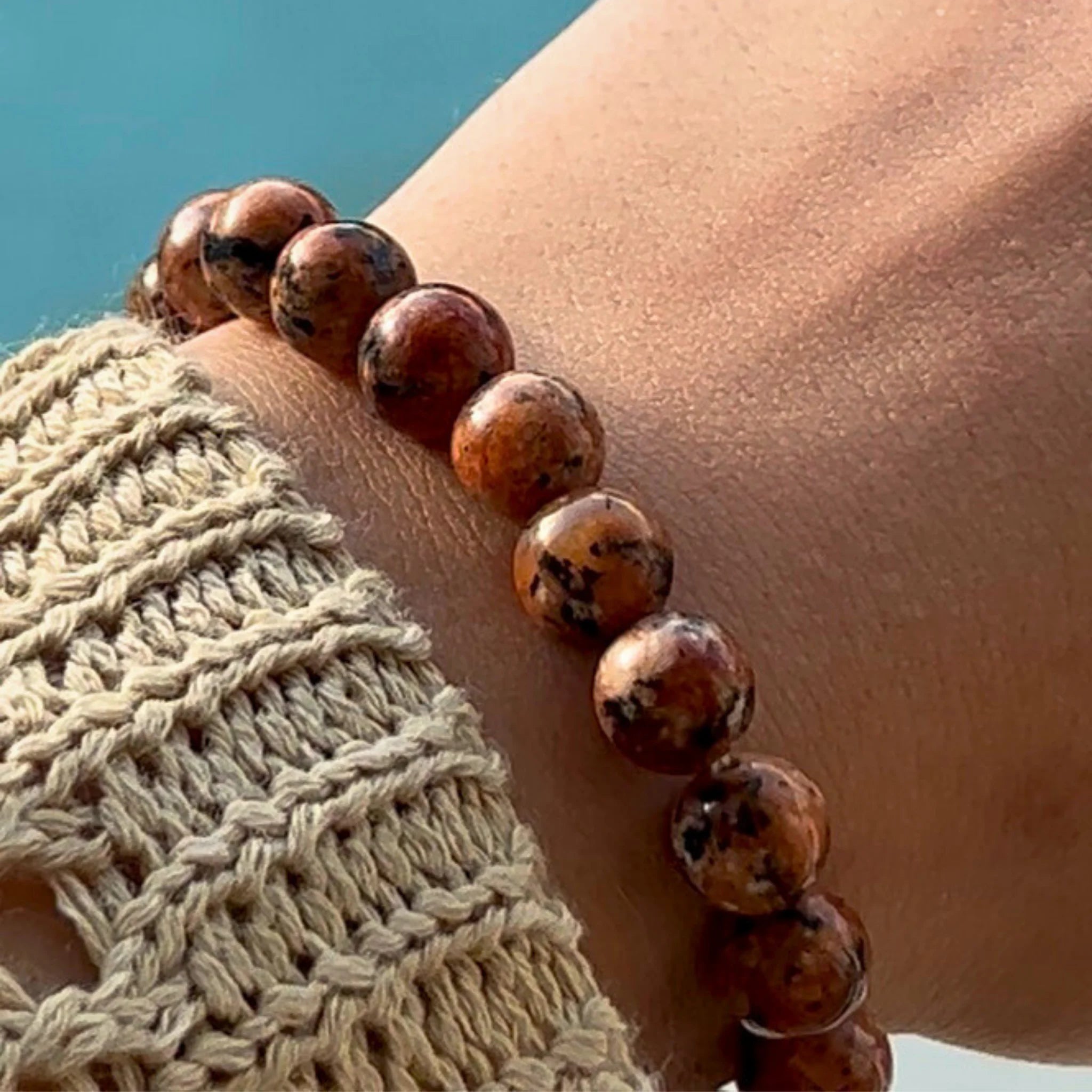 Gemstone4K red leopard skin jasper bracelet worn on wrist outdoors, showing natural patterns and warm red tone.