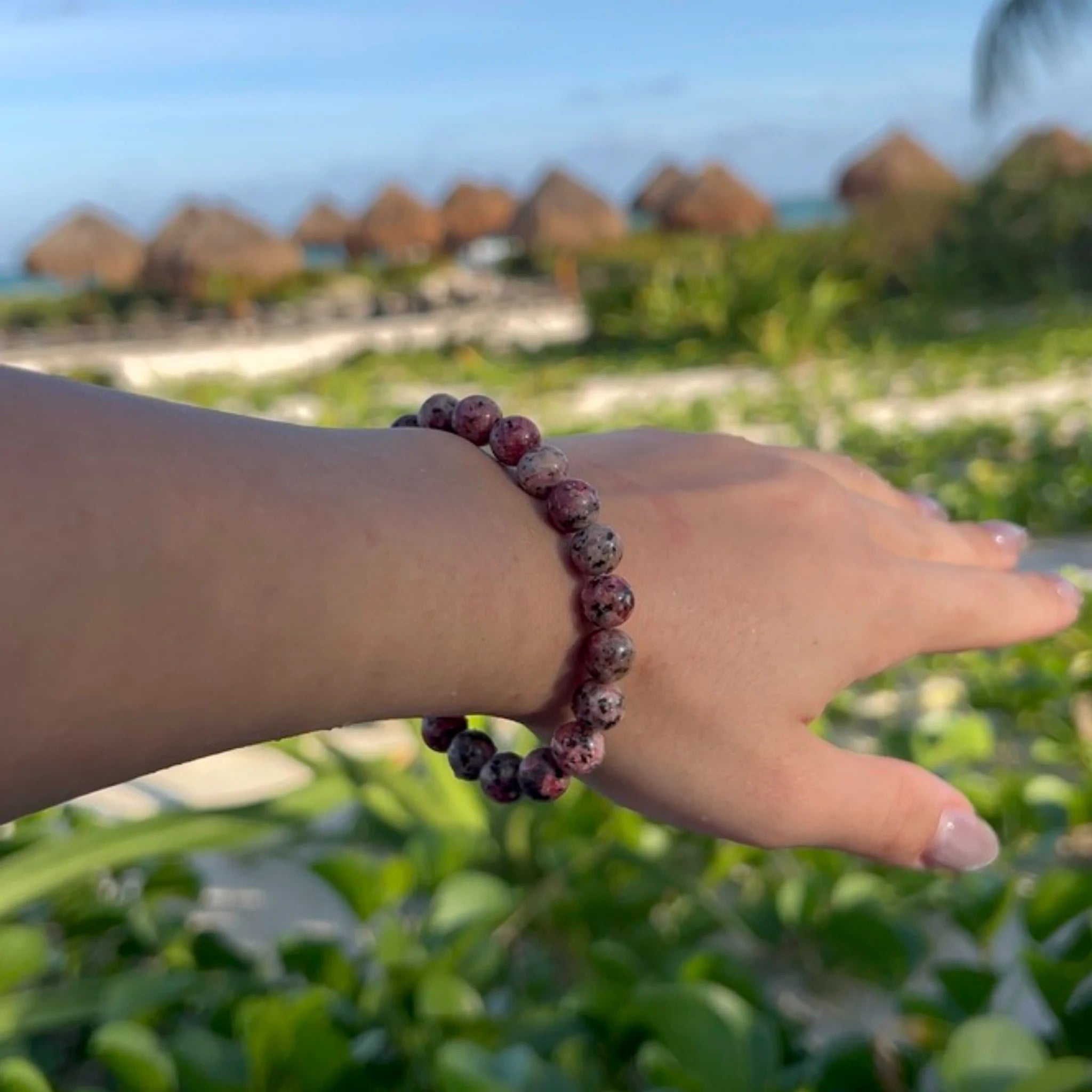 Gemstone4K rhodonite bracelet worn on wrist outdoors, showing pink tones and smooth polished surface.