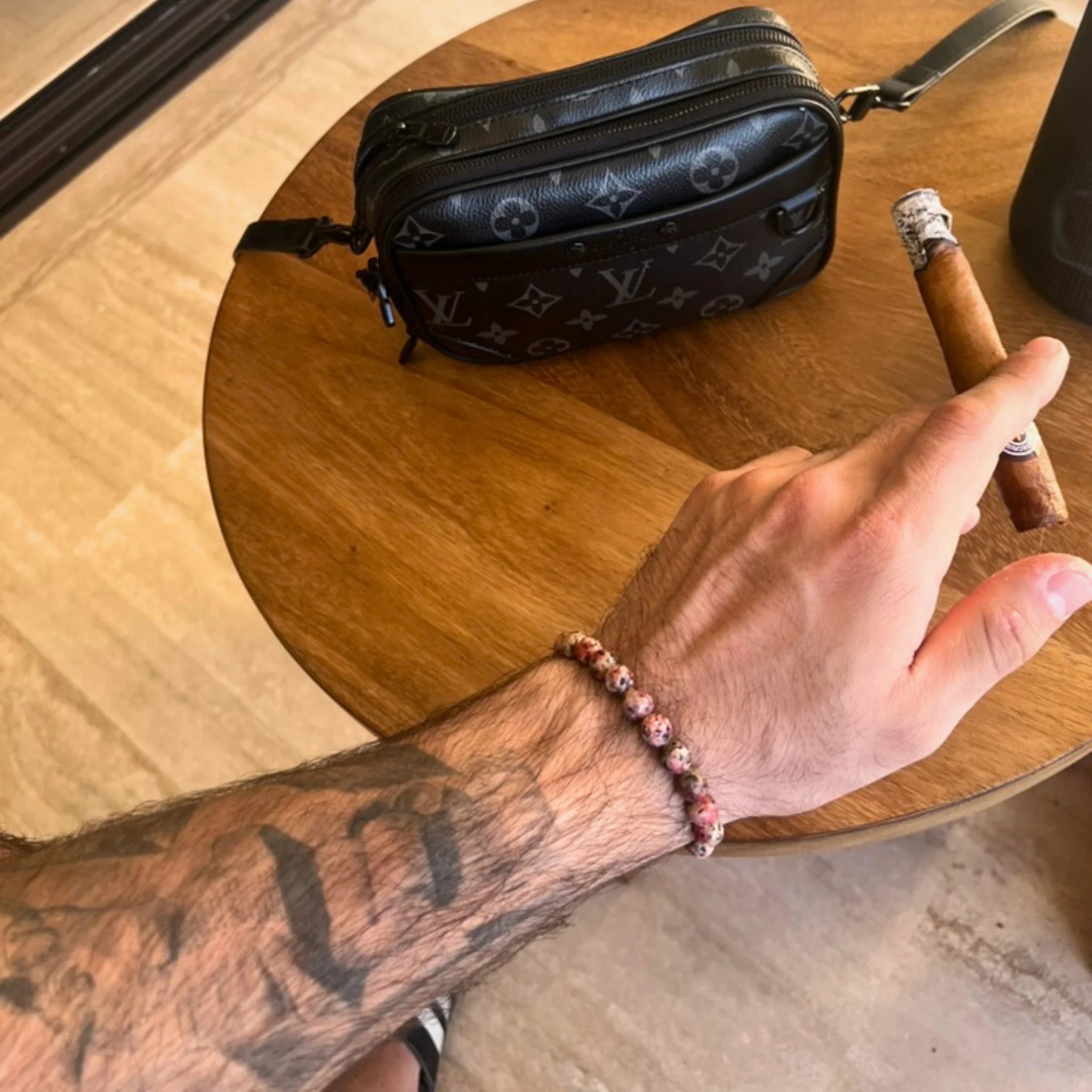 Gemstone4K rhodonite bracelet worn on wrist outdoors, showing pink tones and smooth polished surface.